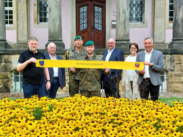 Mit dem Wahlspruch der 3./212 „Muth und Ausdauer“ auf einem „Gelben Band“, das Unterstützung und Verbundenheit mit den Soldatinnen und Soldaten im Einsatz bekundet, werben für den Festakt mit anschließendem geselligen Programm (von links): Jörg Wehmeier, Vorsitzender Arbeitskreis 3./212, Uwe Deppe, Vorsitzender Schützengesellschaft Schötmar, Oberstabsfeldwebel Stephan Hoffschulte, Major Christian Schulte, Andreas Woite, Vorsitzender Stadtsportverband, Myriam Heidemann, Stab S 8 Kommunales und Bürgermeister Dirk Tolkemitt. © Stadt Bad Salzuflen