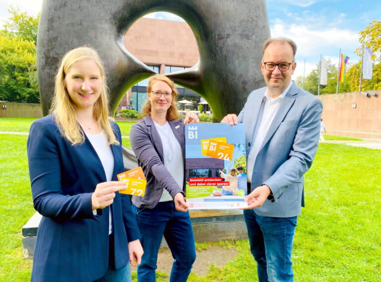 Im Skulpturenpark der Kunsthalle stellen (v.l.) Jacqueline Heger, Bielefeld Marketing), Friederike Langer (moBiel) und Martin Knabenreich (Bielefeld Marketing) die neue Entdecker-Karte für Bielefeld vor. Foto: Bielefeld Marketing