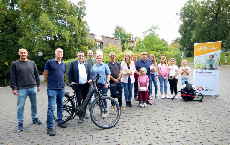 (v.l.) Dennis Hetmann, Mobilitätsmanager des Kreises Lippe, Niels Homann, Gewinner des Pedelecs, Landrat Dr. Axel Lehmann, Christian Bange und Anna-Lena Mügge, Radverkehrsbeauftrage des Kreises Lippe, Karsten Krull, Christine Fricke, Tobias Hempelmann, Walter Reese mit Enkelin und Lehrerin Sandra Völkner mit Schülerinnen und Schüler der Gewinnerklasse der Städtischen Realschule im Schulzentrum Aspe sowie das Maskottchen der Europäischen Mobilitätswoche freuen sich über die Preisverleihung. Foto: Kreis Lippe