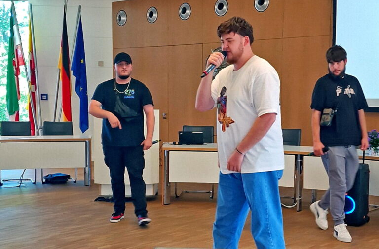 „Rebellion“ im Kreistagssitzungssaal: Almir, Jeremy und Amir (v.l.) performen ihren Rapsong, der auch von Brigitte van Ahee von den „Omas gegen Rechts“ begeistert verfolgt wurde. Foto: Kreis Lippe