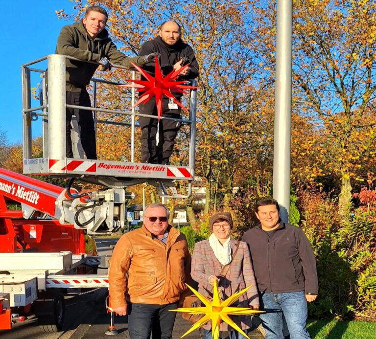 Bei herrlichem Sonnenschein wird die Weihnachtsbeleuchtung aufgehängt: Tim Begemann (links) und Alex Diordiev im Steiger; (vorne v.l.) Stefan Güttler Oerlinghausen Marketing), Tanja Feg (Mitte, Oerlinghausen Marketing) und Michael Makosch (Stadtwerke Oerlinghausen). Fotoquelle: Oerlinghausen Marketing