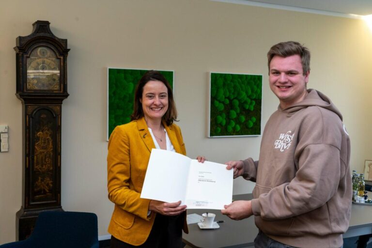 Tim Stiller (20) aus Lage hat in Detmold eine Belobigungsurkunde des Landes NRW von Regierungspräsidentin Anna Katharina Bölling überreicht bekommen. Er hatte im Dezember 2022 einem Autofahrer nach einem Unfall das Leben gerettet. Foto: Bezirksregierung Detmold