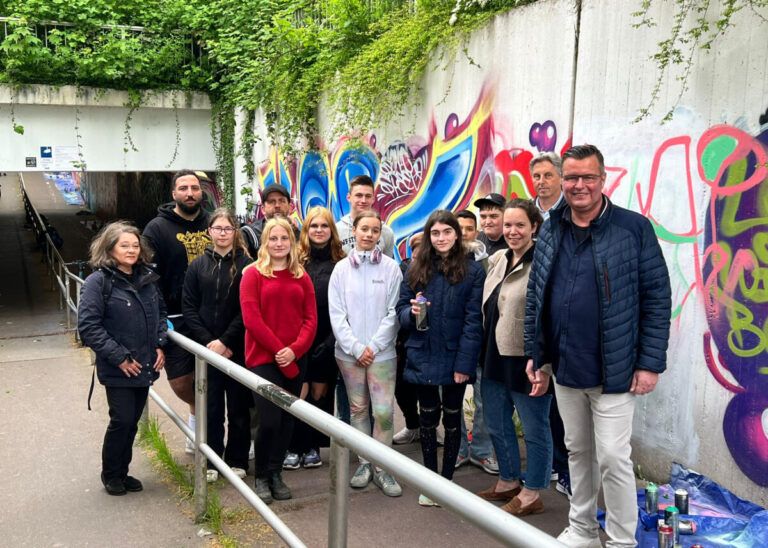 Vor den fast fertigen Kunstwerken in der Unterführung: (v.r.) Thomas Mahlmann, Jörg Pohlmann (3.v.r.) und Schulleiterin Dorothee Kriener. (v.l.) Anita Millard und Monib Sadat sowie Daniel Schneider (4.v.r.) mit den Schülerinnen und Schülern der Albert-Schweitzer-Schule. Foto: Lippe Bildung eG