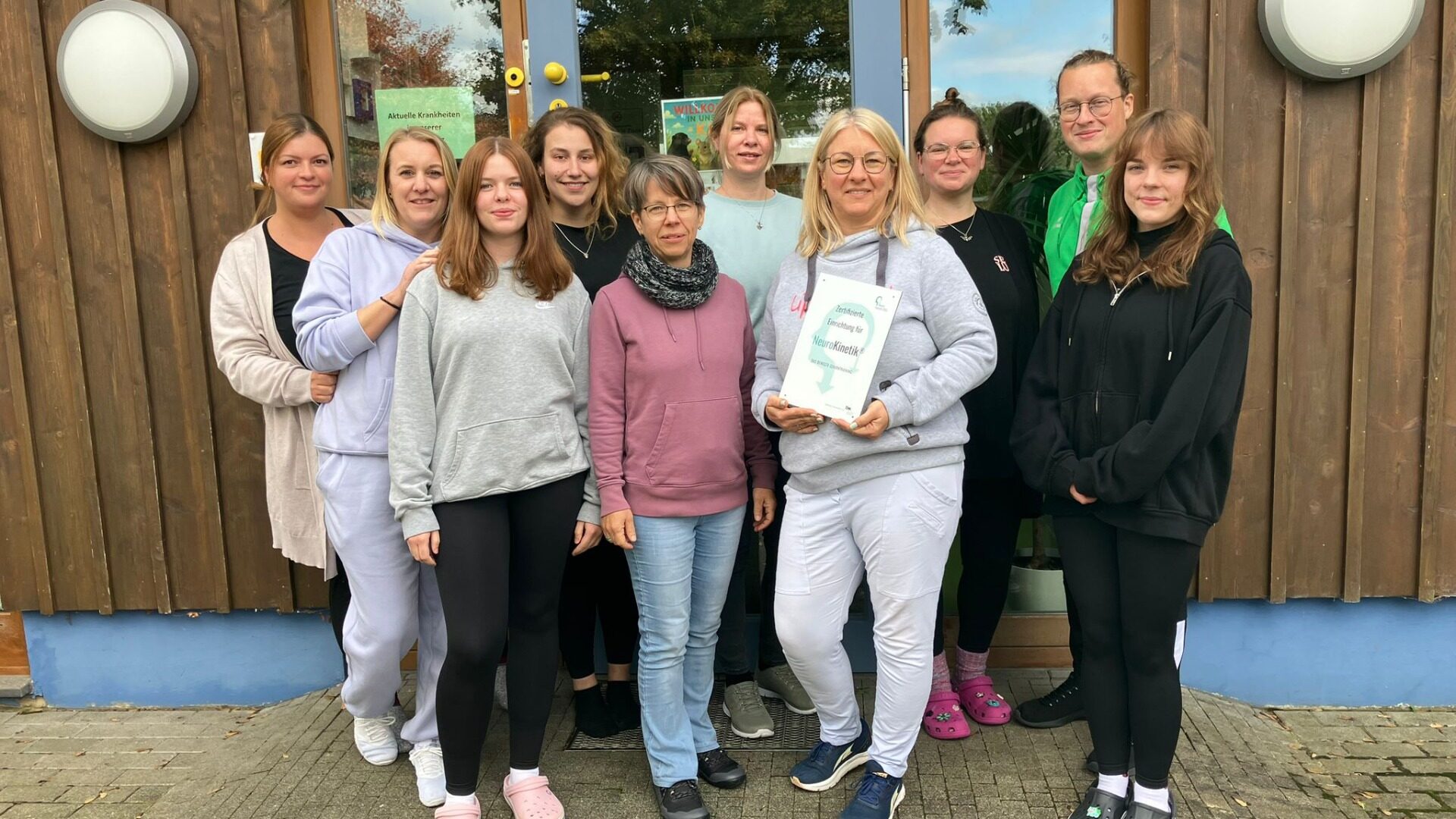Das Schild bescheinigt den Kita-Beschäftigten und der Leiterin Nicole Reiß (4. v. rechts), Experten für Neurokinetik zu sein. Foto: Privat