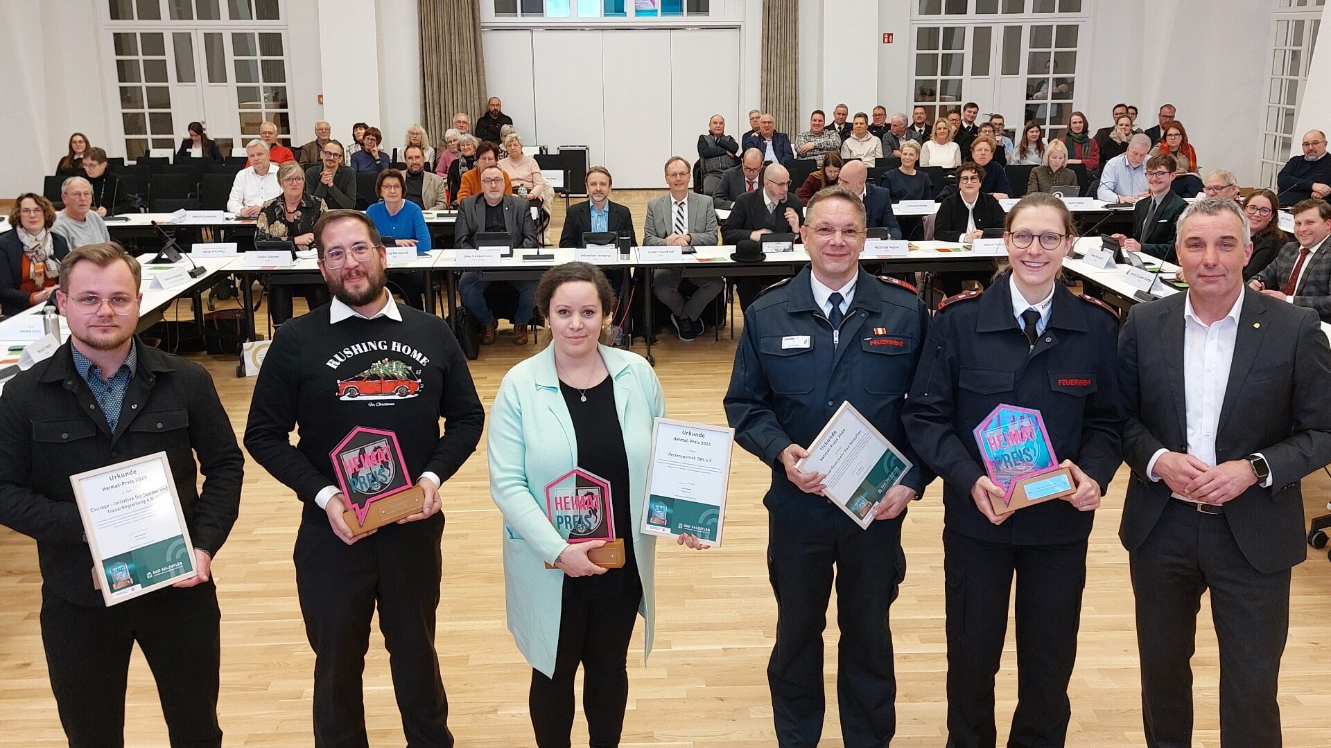 Feierliche Verleihung des Heimat-Preises 2025 im Galasaal des Kurhauses: Bürgermeister Dirk Tolkemitt (rechts) überreichte die Awards und Urkunden an (v.l.) Jason Maximilian Jochem und Kevin Kößler (beide Courage - Initiative für Sterbe- und Trauerbegleitung), Jasmin Lühring (Herzenswunsch OWL) sowie Martin Sohl und Corinna Stakelbeck (beide Kinderfeuerwehr Bad Salzuflen). Foto: © Stadt Bad Salzuflen