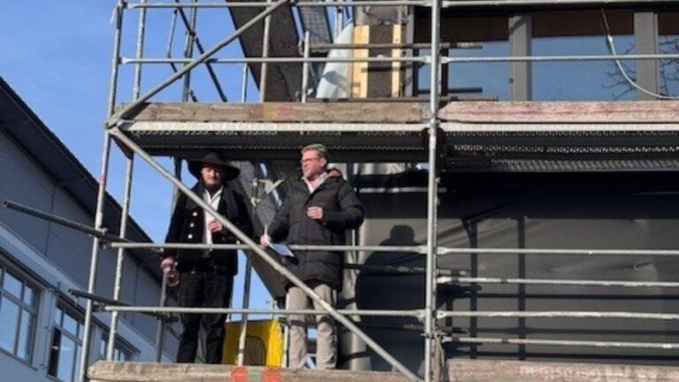 Kurz vor dem Richtspruch: Zimmermann Henrik Sonnenburger und Bürgermeister Peter Heepmann auf dem Gerüst des voranschreitenden Erweiterungsbaus der Grundschule Helpup. Foto: Stadt Oerlinghausen