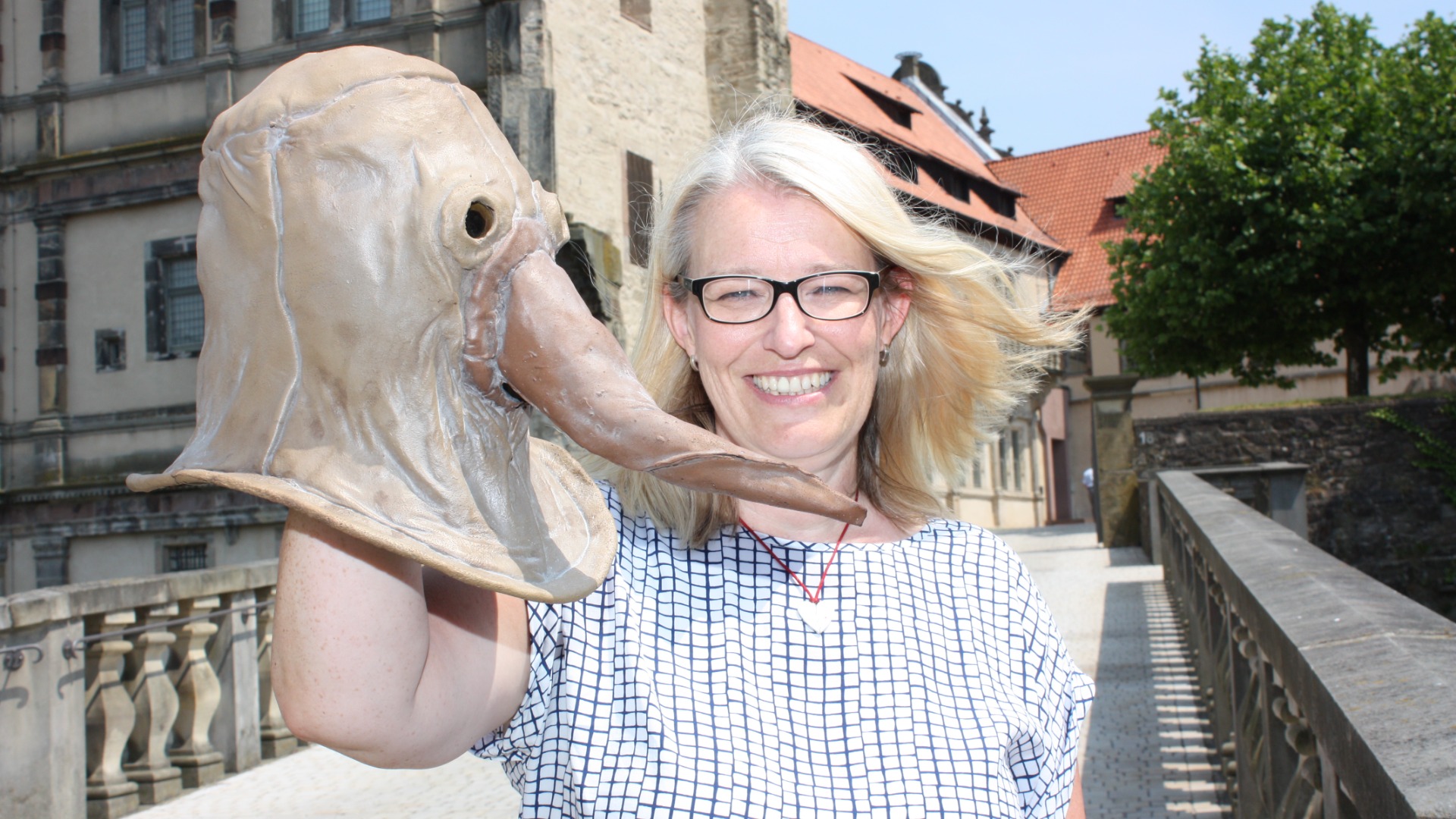 Dr. Susanne Hilker zeigt eine Pestmaske, die in der Zeit der Weserrenaissance vor Krankheiten schützen sollte. Foto: Weserrenaissance-Museum Schloss Brake, Herrmann