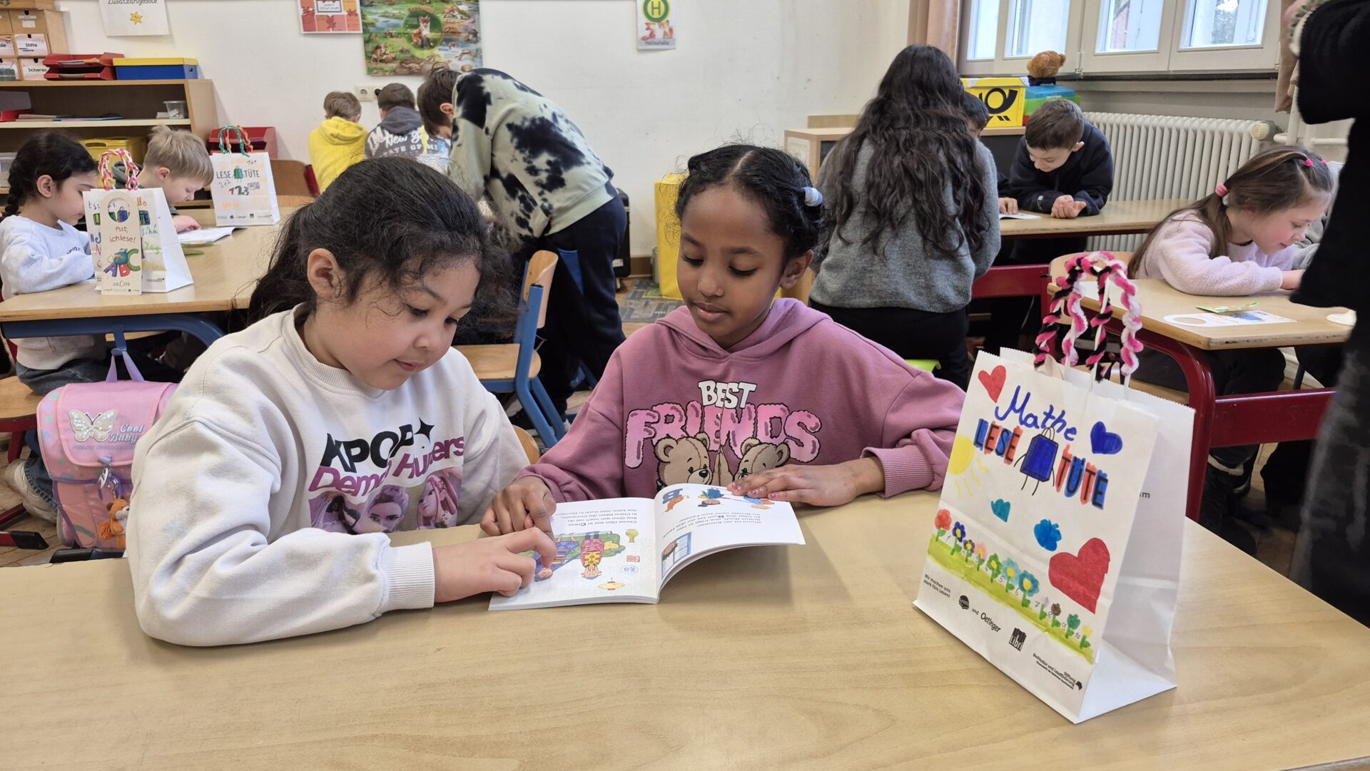 Zeile für Zeile: Amira (rechts), Viertklässlerin der Grundschule Ahornstraße, begleitet Aaliyah beim Lesen ihres neuen Erstlesebuches. Fotos: Christina-Carolin Rempe/ Stiftung Standortsicherung