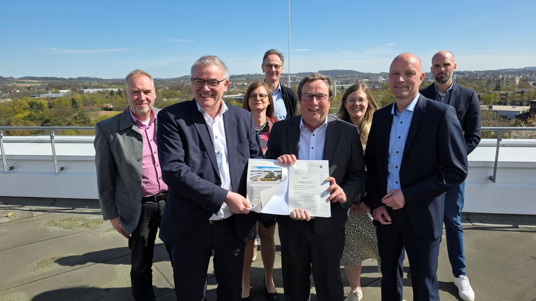 Umweltminister Oliver Krischer (Mitte) und Jens Kronsbein, Leiter der Abteilung Regionale Entwicklung bei der BezReg (rechts), überreichen Rainer Grabbe (links) und dem Projektteam beim Kreis Lippe den Förderbescheid für die Umsetzung der klimaangepassten Außenanlagen am Kreishaus. © Kreis Lippe