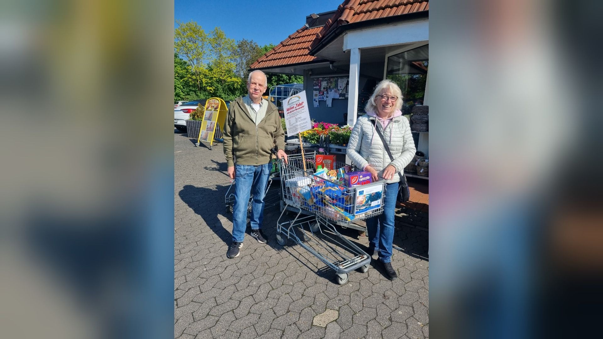 Mann und Frau stehen mit gefüllten Einkaufswagen vor einem Laden für eine Tafel-Aktion