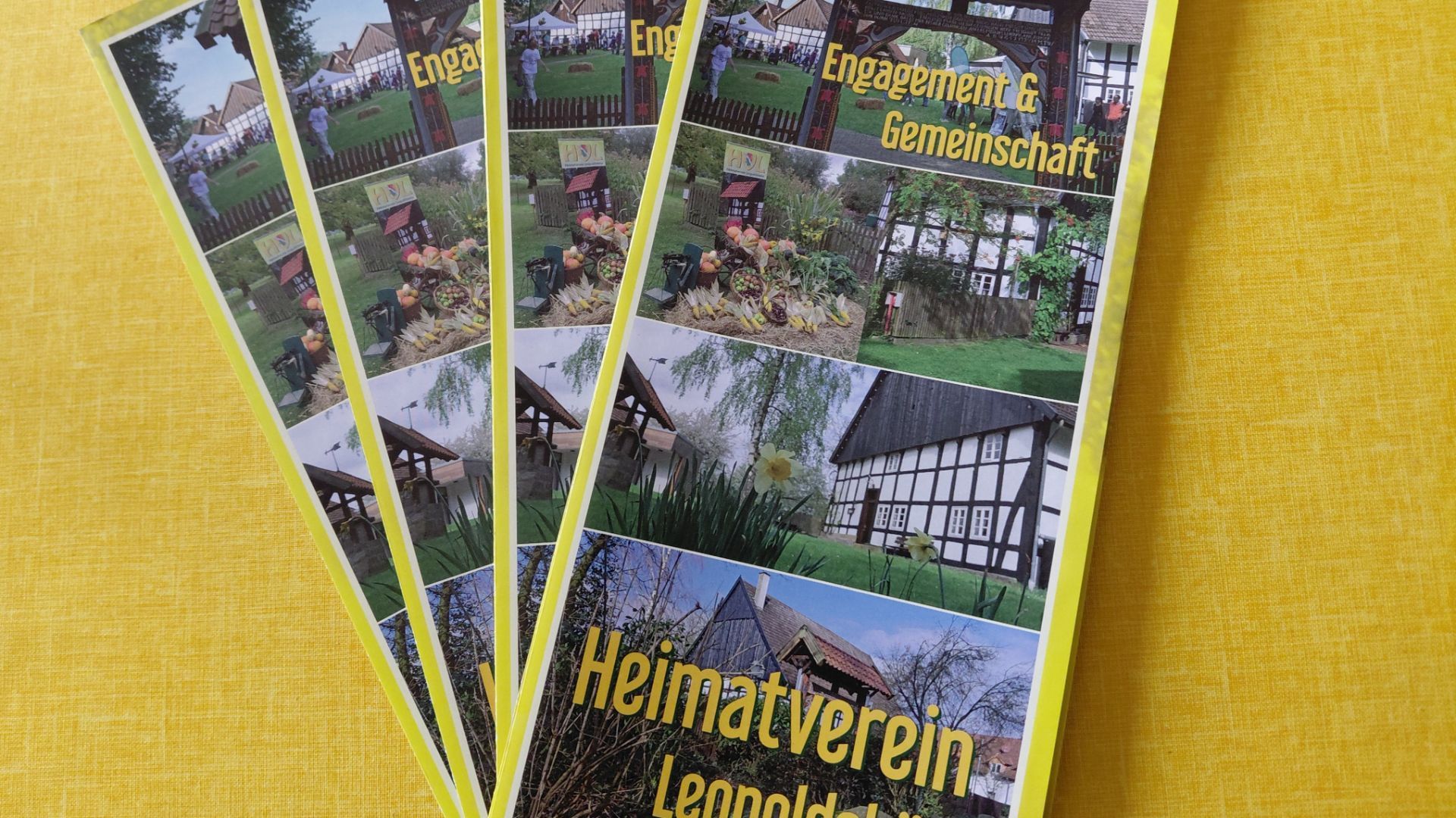 Mehrere Informationsflyer des Heimatvereins Leopoldshöhe zeigen Fachwerkbauten, Dorfleben und Herbstdekorationen