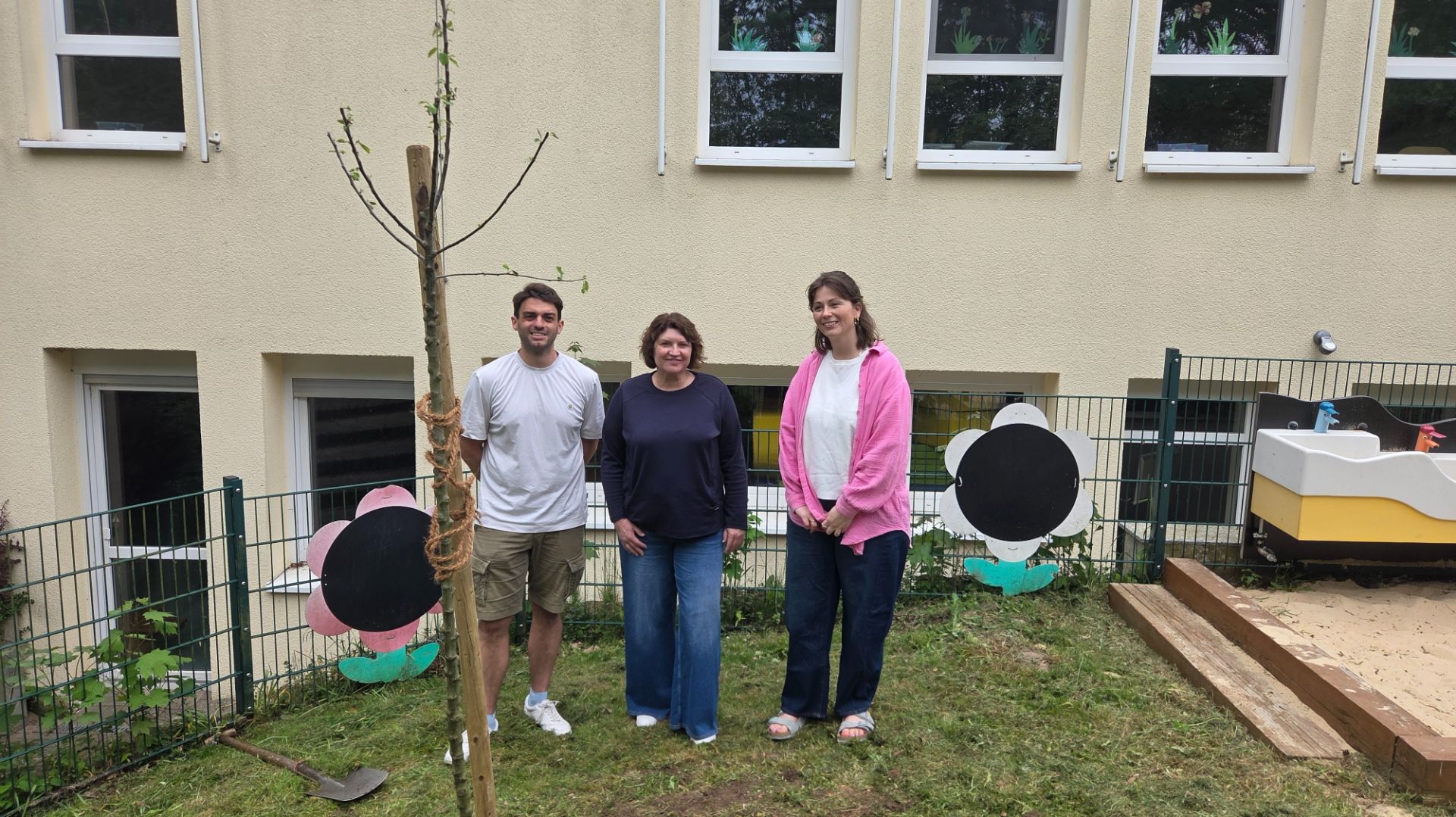 Drei Personen, Ellen Stock, Tobias Schilling und Annelie Kerker-Schulte, stehen nach dem Pflanzen eines Apfelbaums vor
