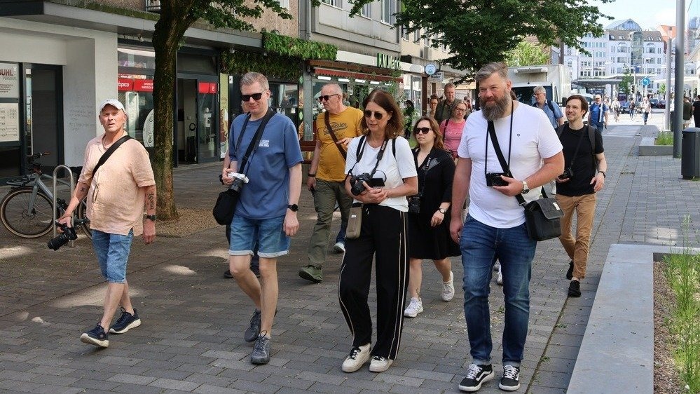 Eine Gruppe von Fotografen geht mit Kameras bei Tageslicht auf einem Bürgersteig in Bielefeld