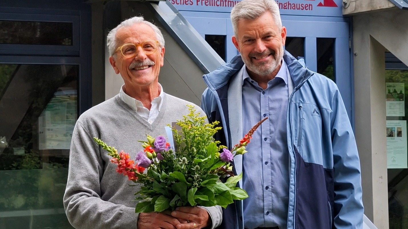 Ilemann mit Blumenstrauß neben Dirk Becker lächeln vor dem Archäologischen Freilichtmuseum