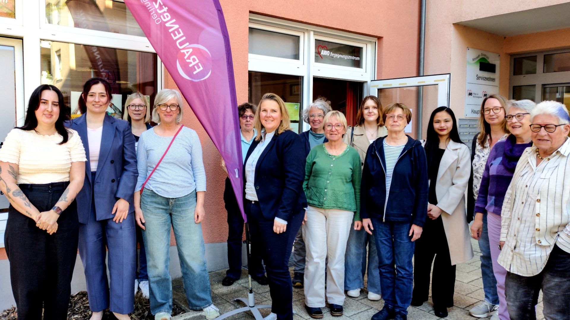 Eine Gruppe von etwa 15 Frauen verschiedenen Alters lächelt für ein Gruppenfoto vor einem Gebäude mit AWO- und
