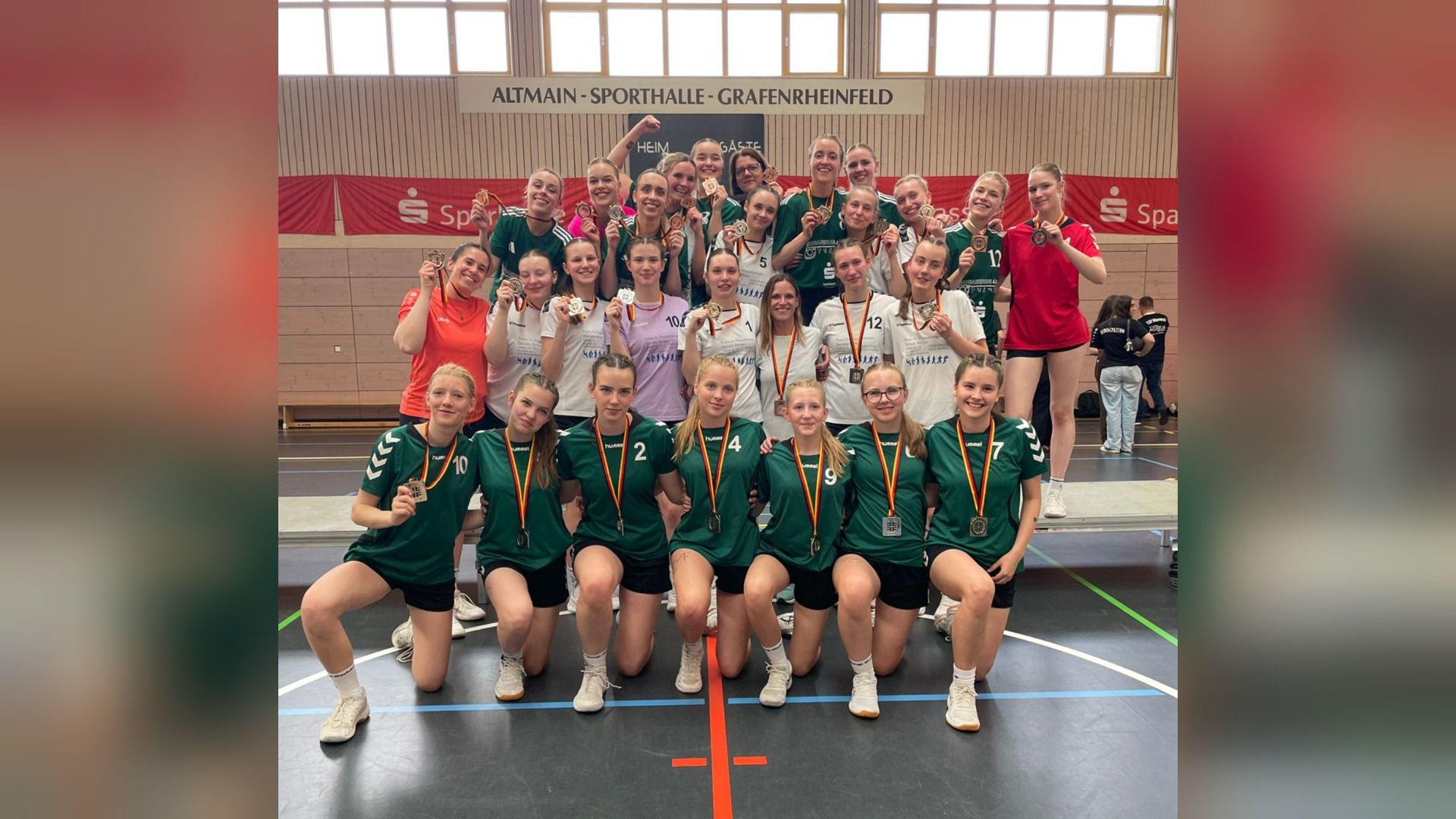 Eine Gruppe lächelnder Korbballerinnen mit Silber- und Bronzemedaillen posiert in der Altmain-Sporthalle Grafenrheinfeld