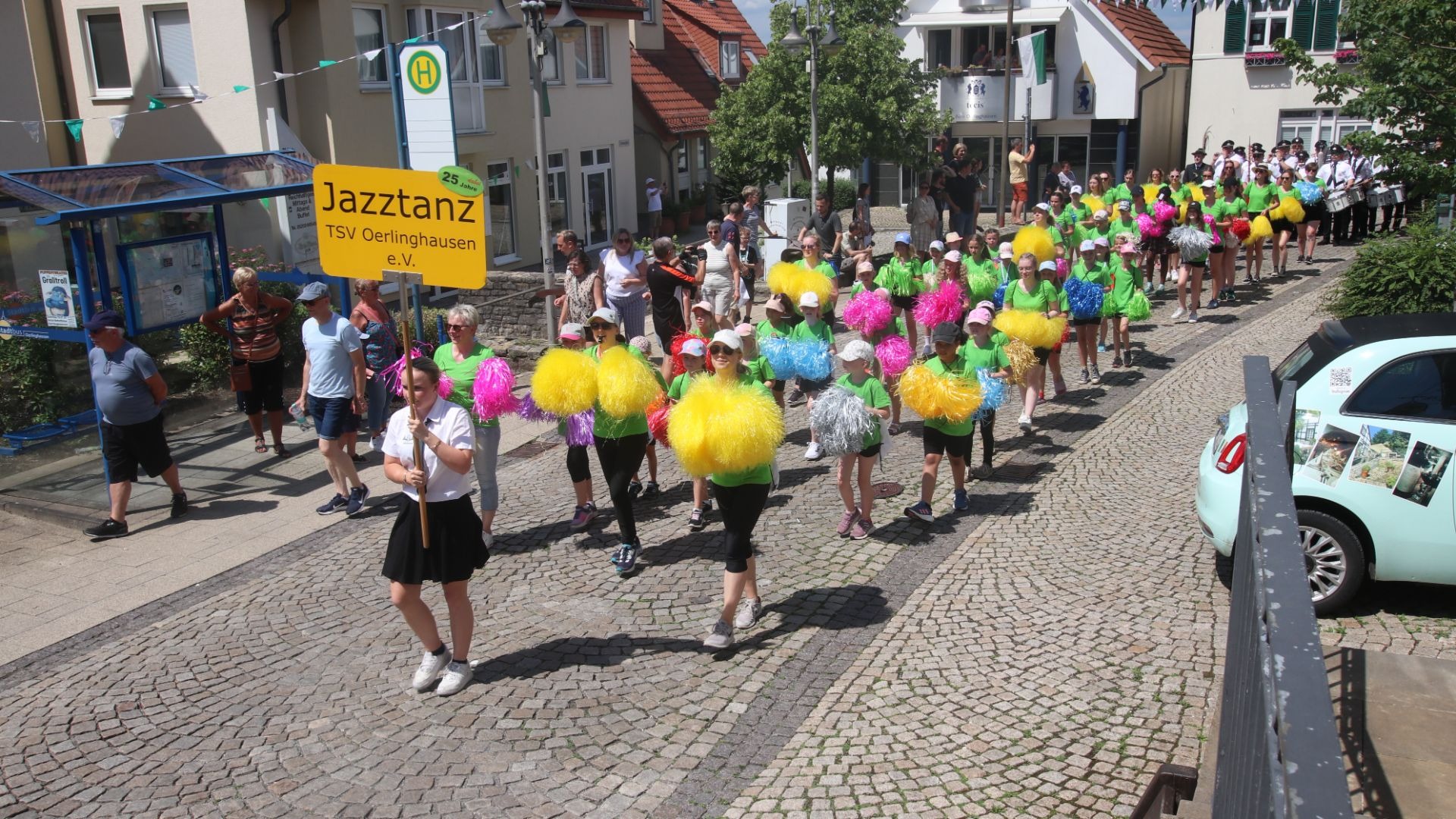 Kinder und Jugendliche des TSV Oerlinghausen marschieren als Jazztanzgruppe mit bunten Pompons auf einer