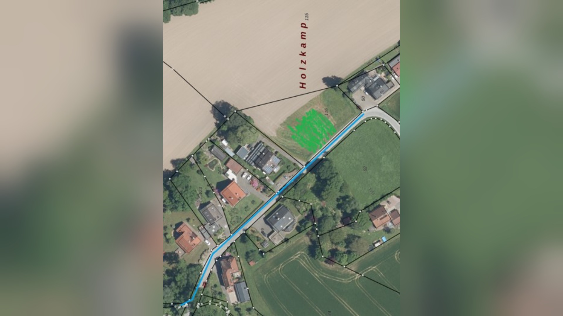 Luftbild des Wohngebiets Holzkamp mit Feldern, blau markierter Entwässerungsleitung und grün markierter Baufläche
