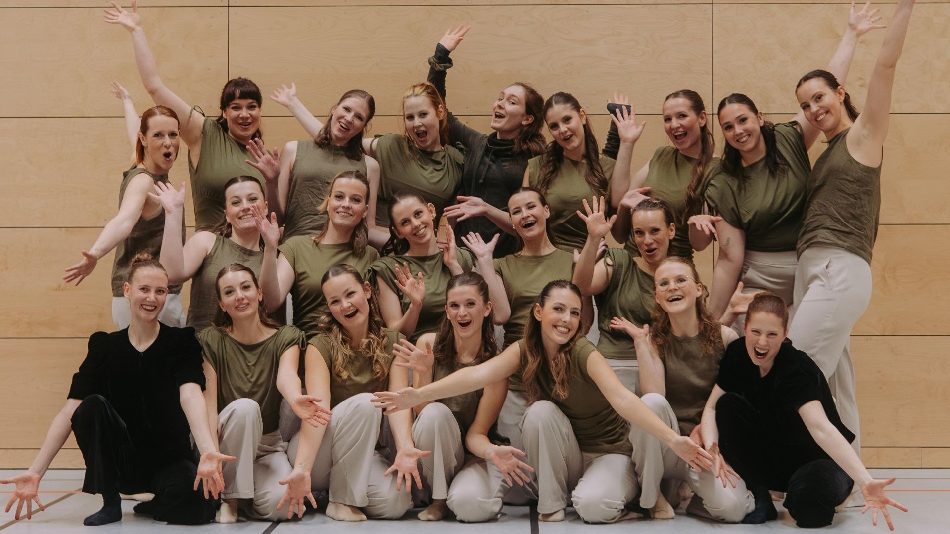 Das Tanzteam TC Metropol posiert lachend und in Sportkleidung in einer Sporthalle
