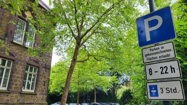Blaues Parkschild mit drei Zusatzschildern: Parken von 8 bis 22 Uhr für maximal 3 Stunden, vor einem alten Steinhaus