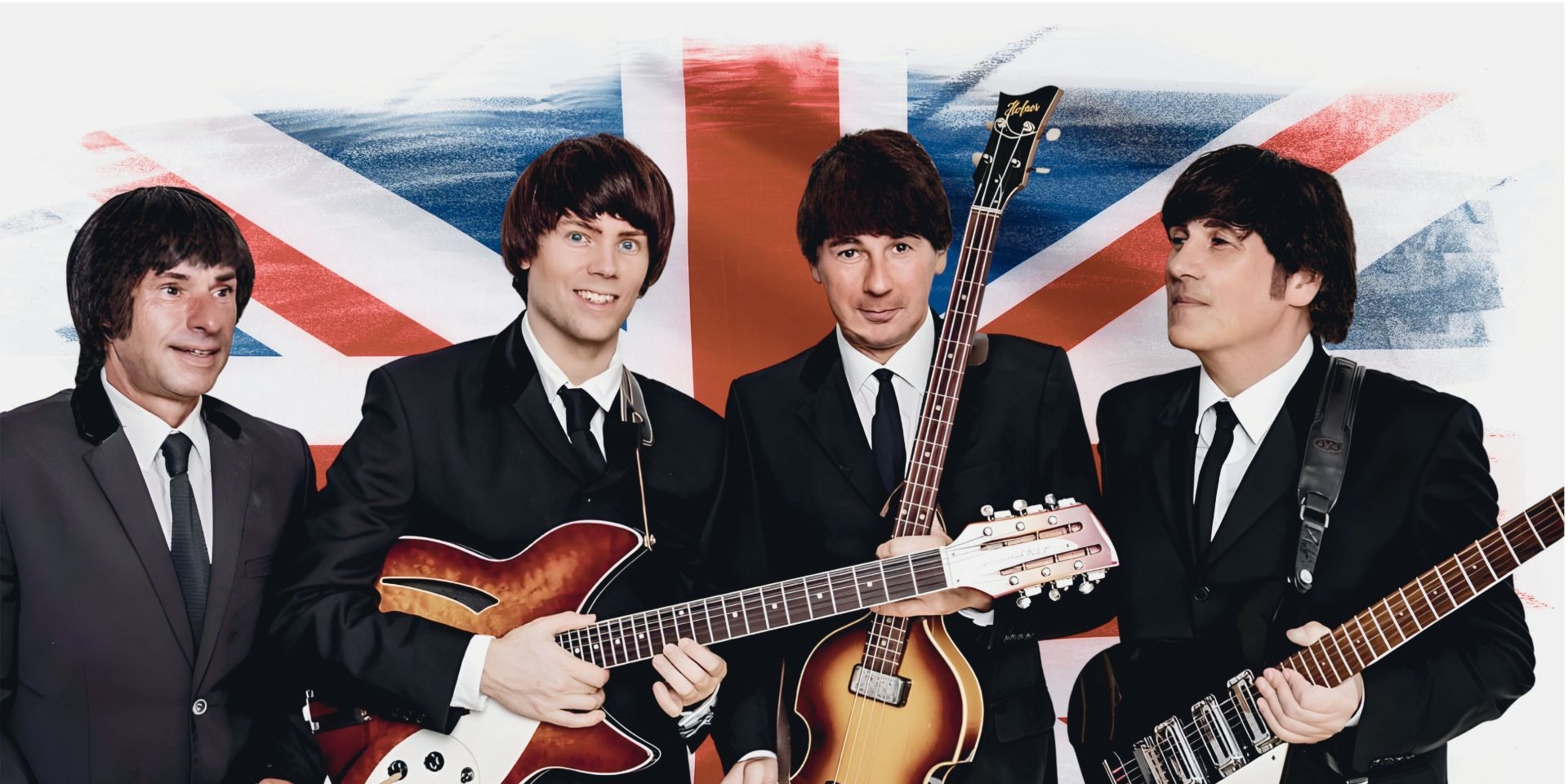 Vier Musiker in dunklen Anzügen mit Gitarren und Mop-Top-Frisuren vor britischer Flagge