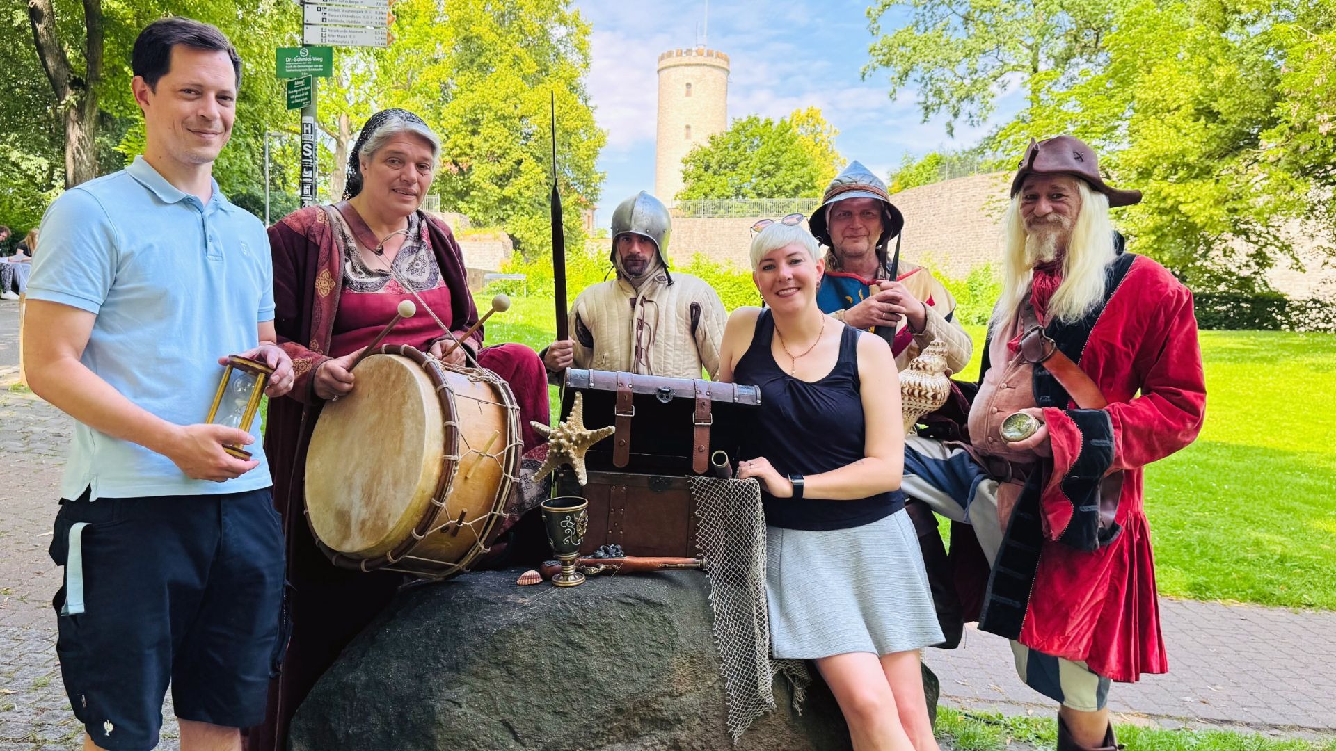 Sechs Personen, teils in Alltagskleidung, teils in Mittelalter- und Freibeuterkostümen, posieren vor der Sparrenburg