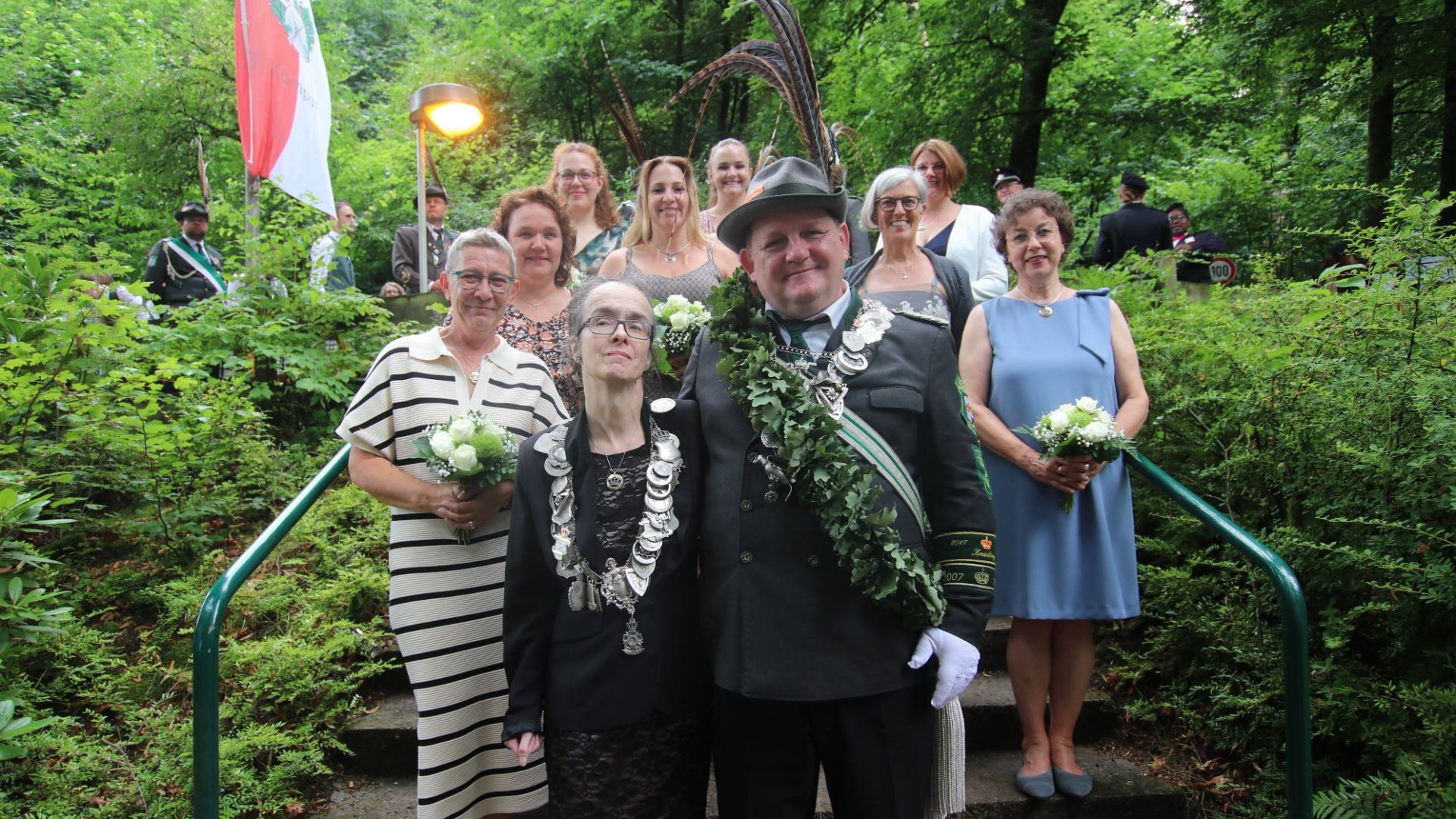 Eine Gruppe von Männern und Frauen in festlicher Kleidung, darunter ein Schützenkönigspaar mit Orden und Eichenlaub,