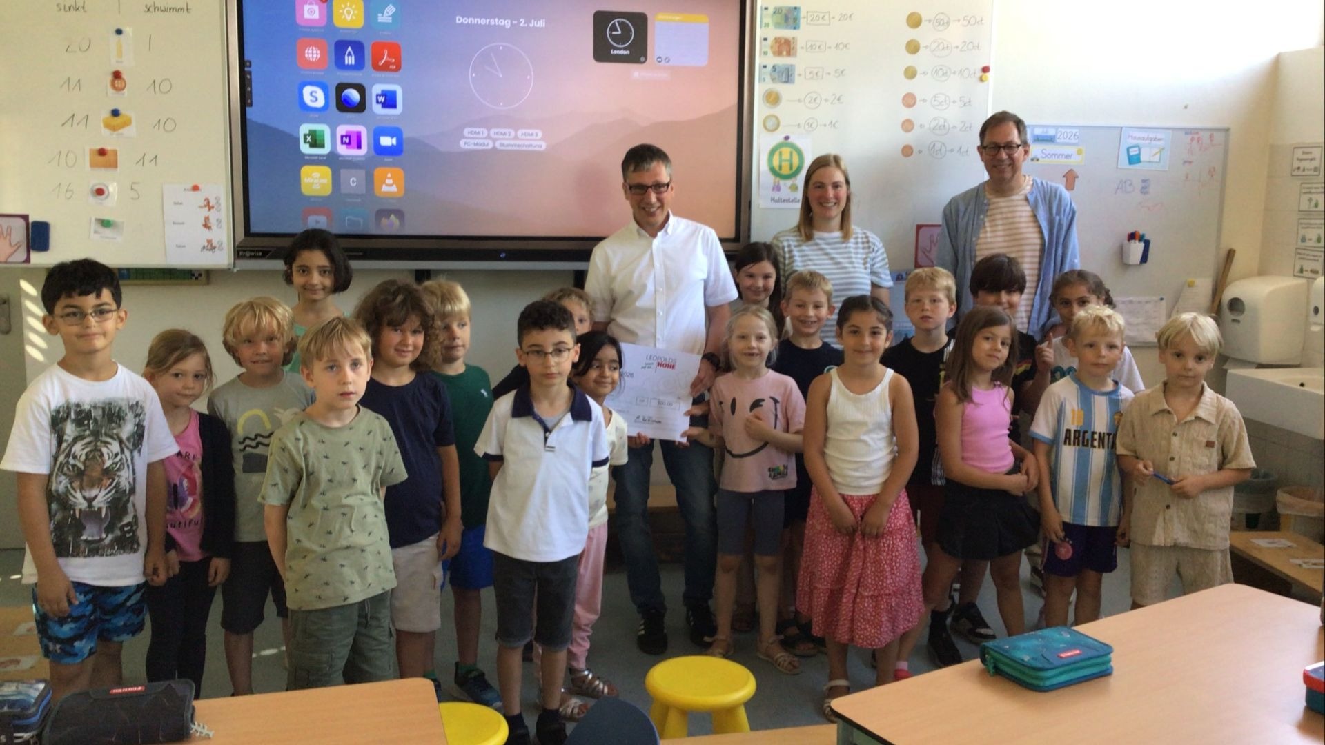 Gruppe von etwa 20 Leopoldshöher Grundschülern mit drei Erwachsenen posiert in einem Klassenzimmer mit Urkunde