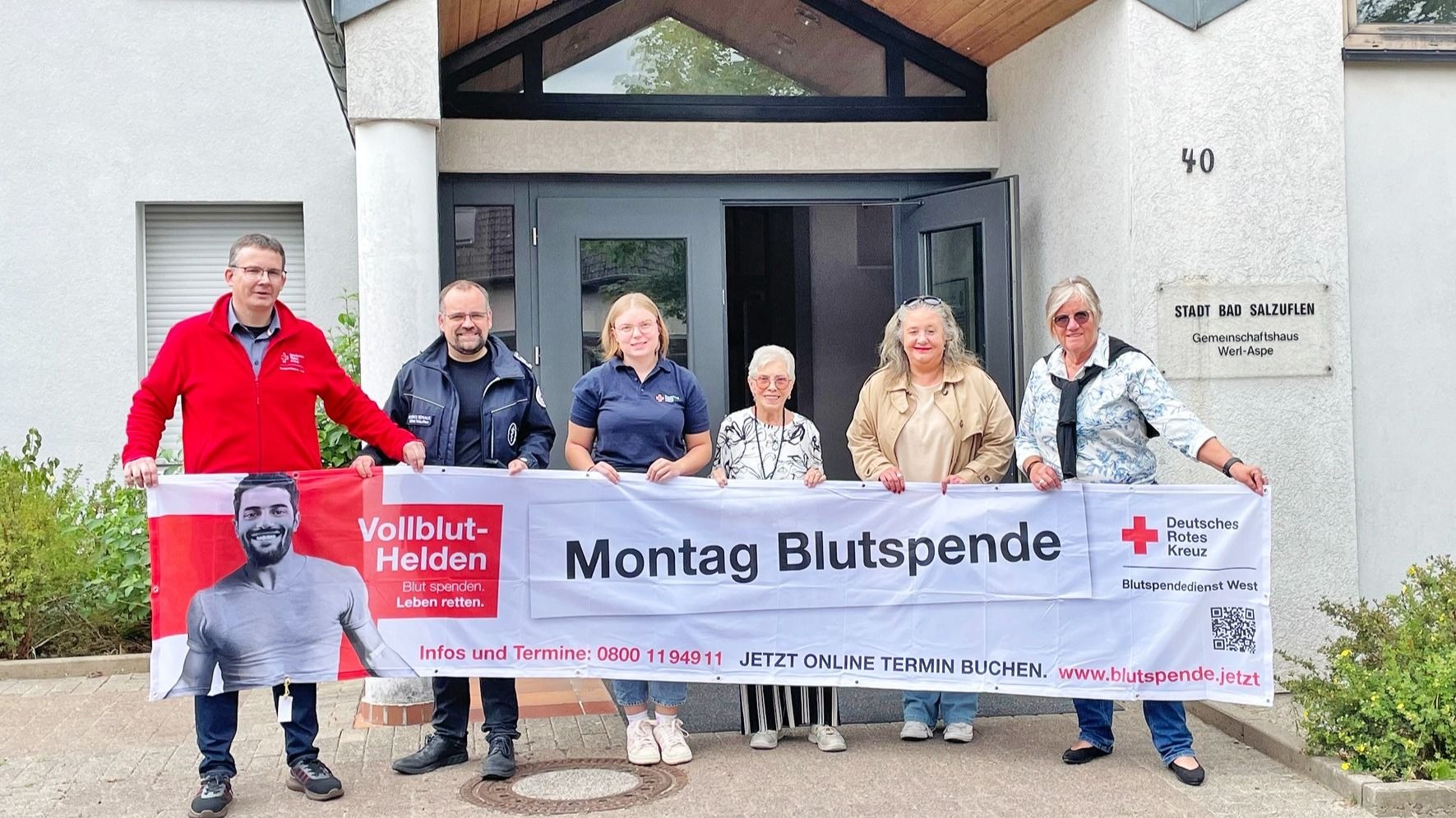 Drei Männer und drei Frauen halten ein Blutspende-Banner vor dem Gemeinschaftshaus Werl-Aspe in Bad Salzuflen