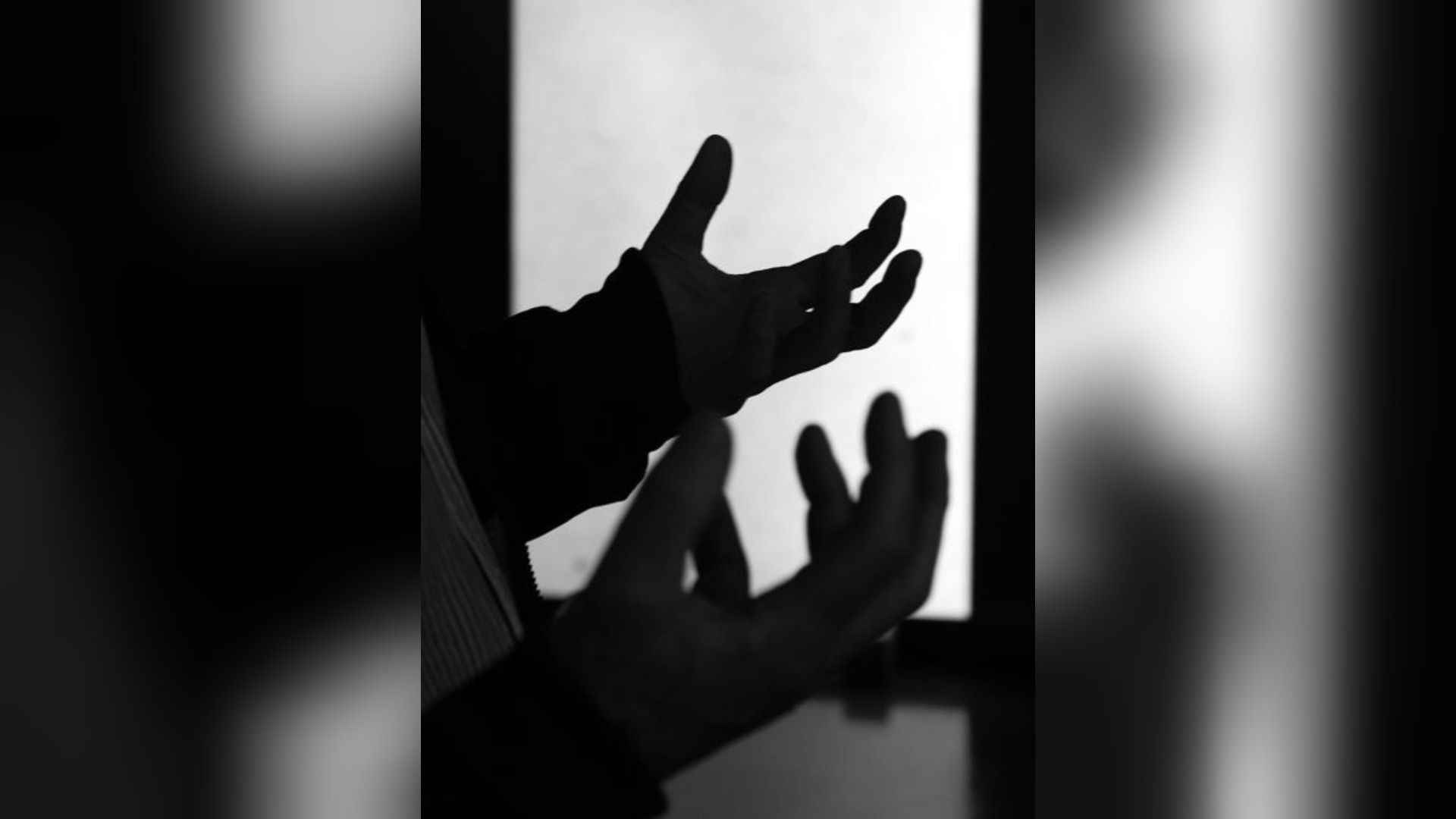Hände einer Person mit offenen Handflächen vor einem hellen, rechteckigen Bereich