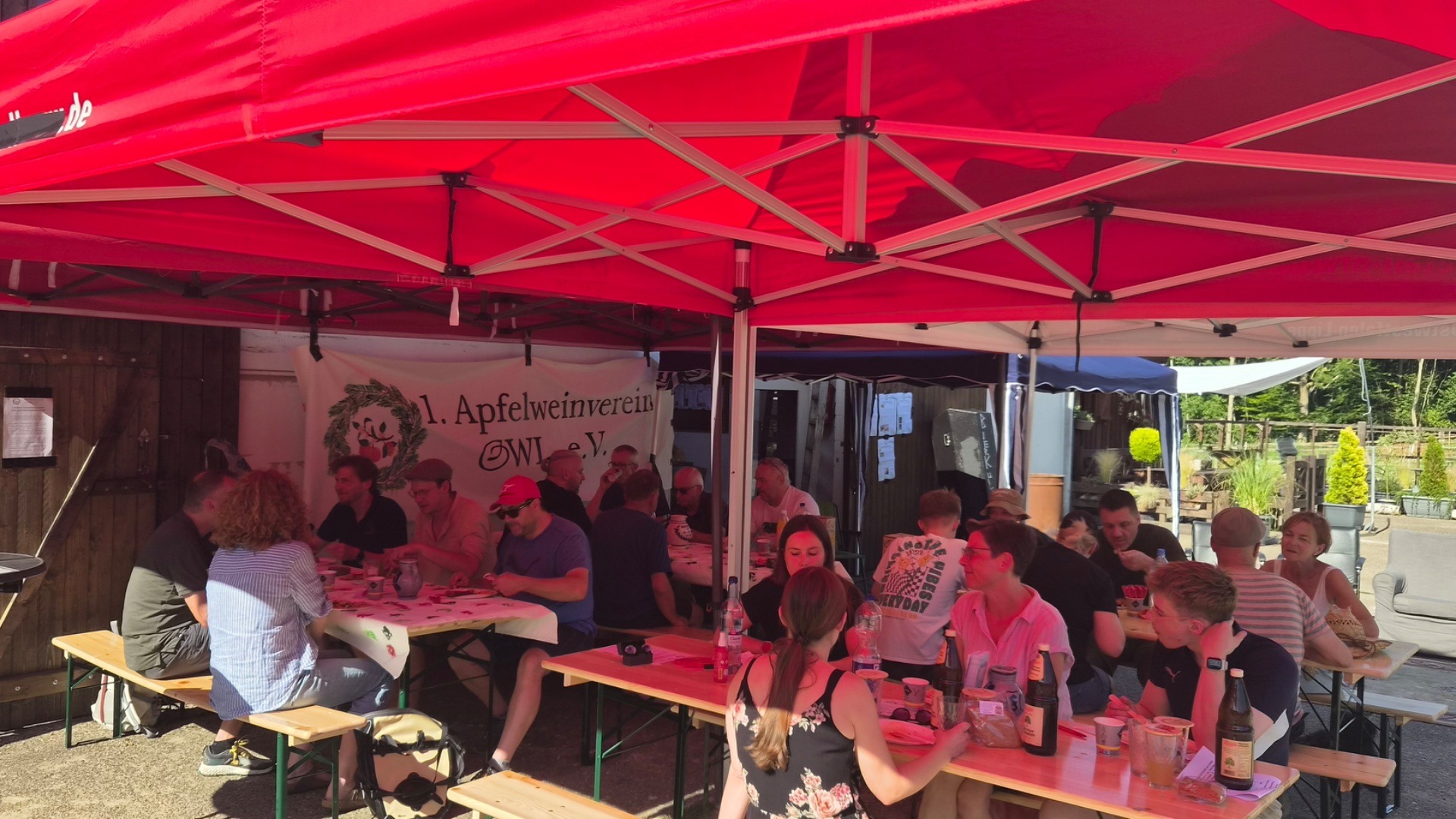 Sommerfest des 1. Apfelweinvereins OWL e.V. mit vielen Gästen, die unter roten Zelten an Tischen sitzen