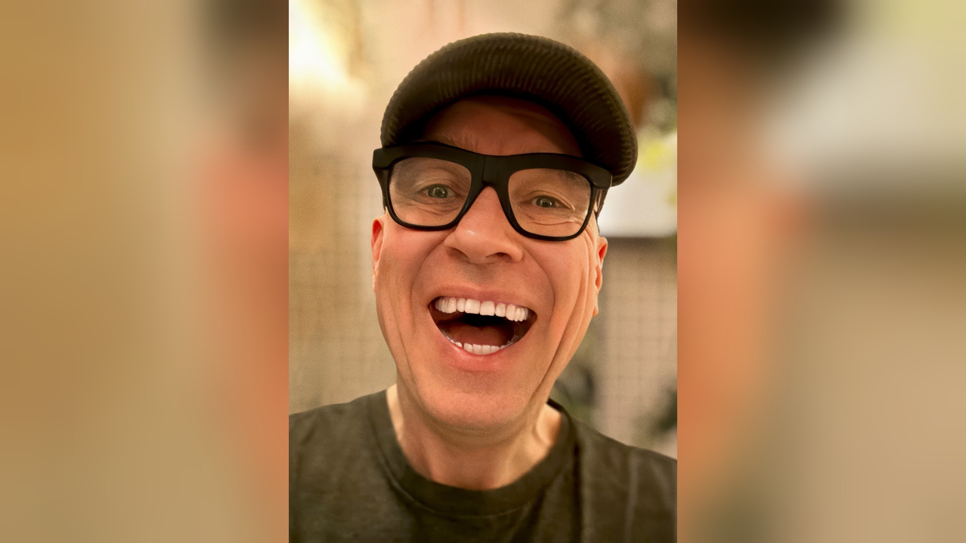 HG Butzko lacht herzlich mit offenem Mund, trägt dunkle Mütze und schwarze Brille