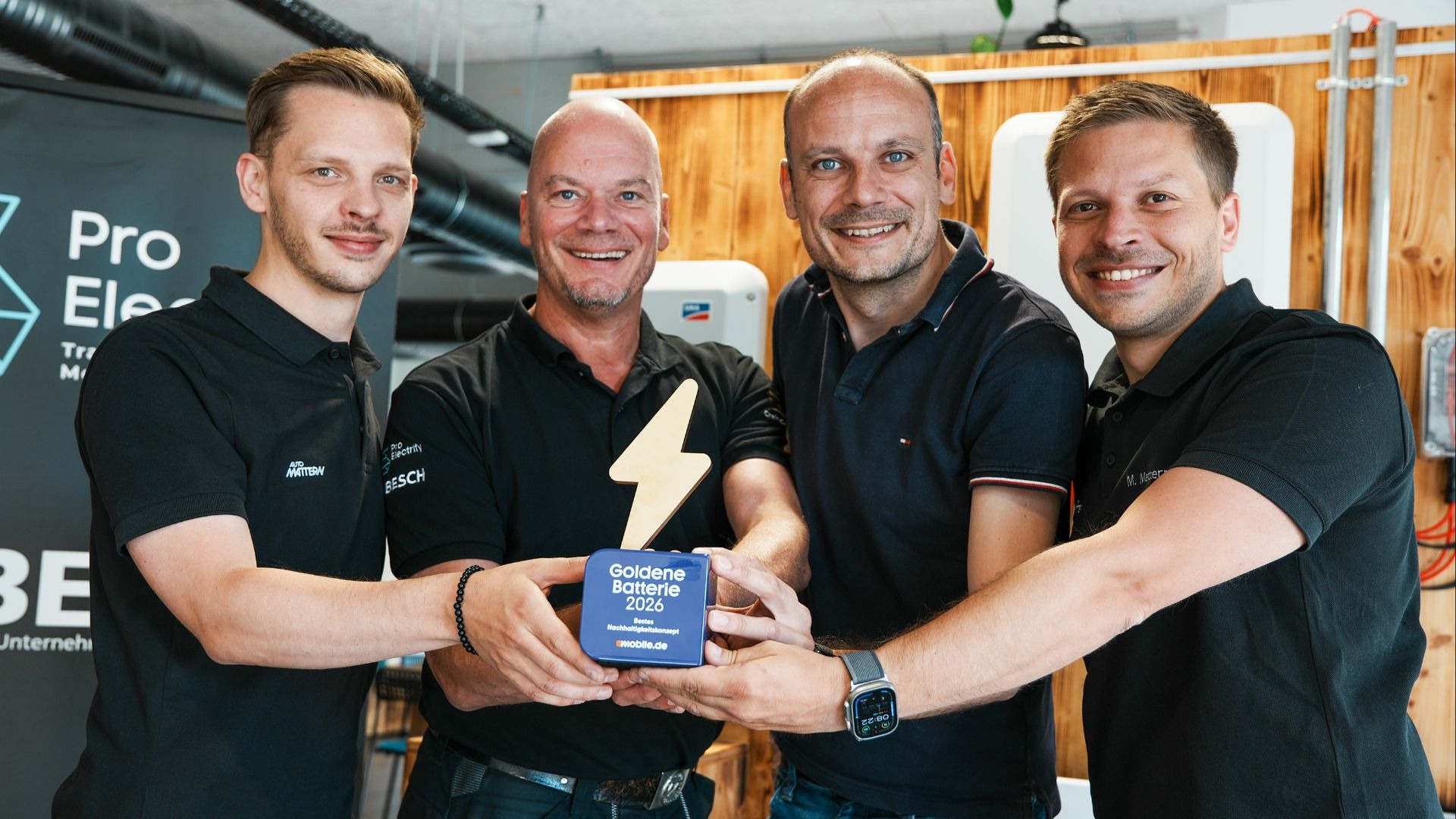 Vier lächelnde Männer von Auto Mattern und ProElectrify halten gemeinsam die blaue Trophäe "Goldene Batterie 2026