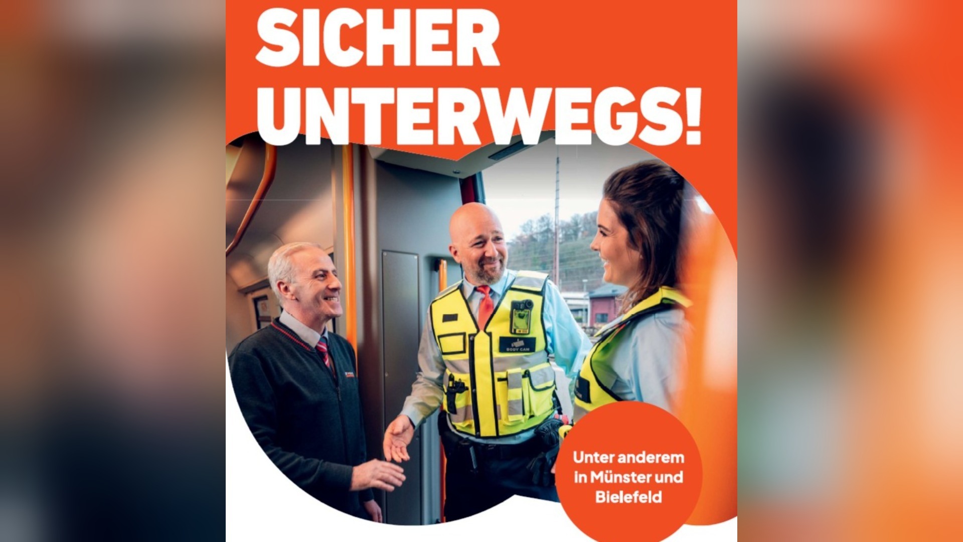 Drei lächelnde Personen in Uniformen und Warnwesten im Gespräch in einem Nahverkehrszug