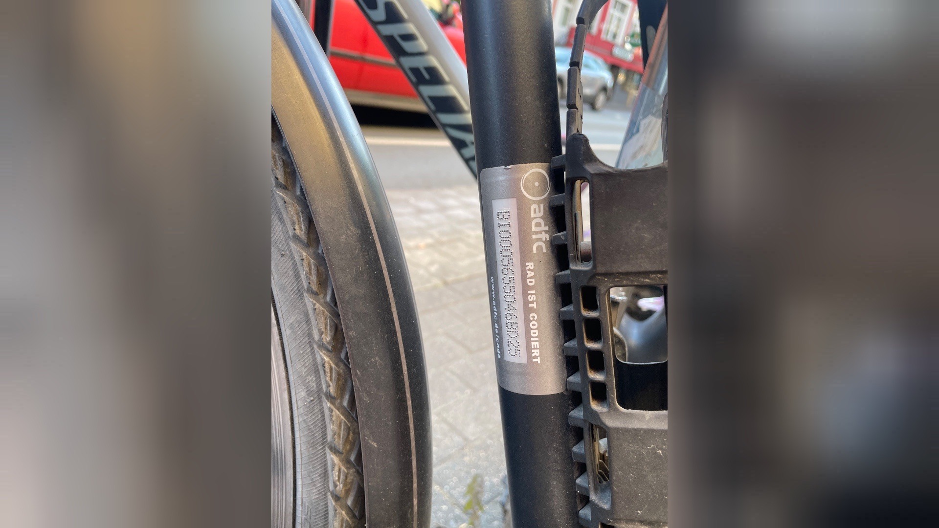 Nahaufnahme eines silbernen ADFC-Aufklebers "RAD IST CODIERT" mit Code auf schwarzem Fahrradrahmen