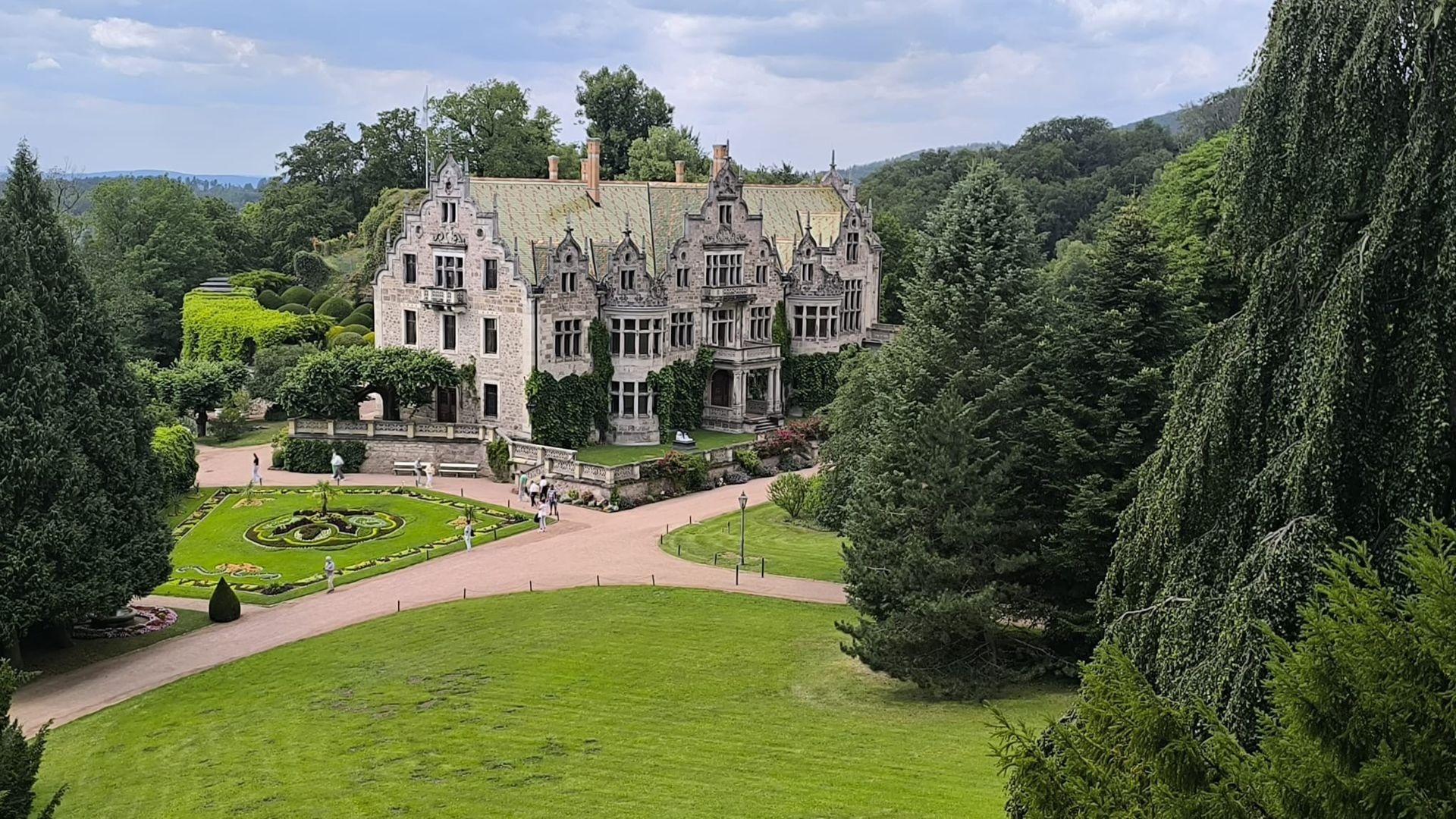 Schloss Altenstein, ein großes, steinernes Gebäude mit Türmen und grünem Dach, umgeben von weitläufigen Parkanlagen mit