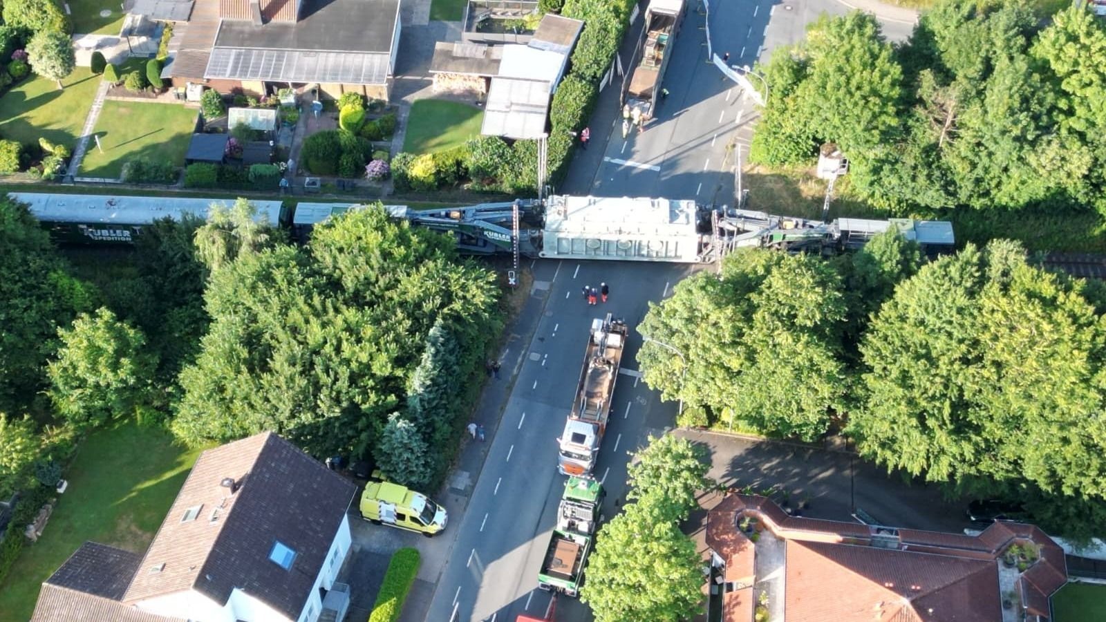 Luftaufnahme: Ein großer Trafo auf einem Tieflader kreuzt eine Wohnstraße in Leopoldshöhe, umgeben von Häusern und