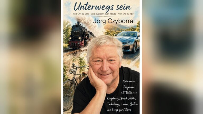 Jörg Czyborra lächelt, im Hintergrund eine Dampflok, ein modernes Auto und ein altes Fahrrad