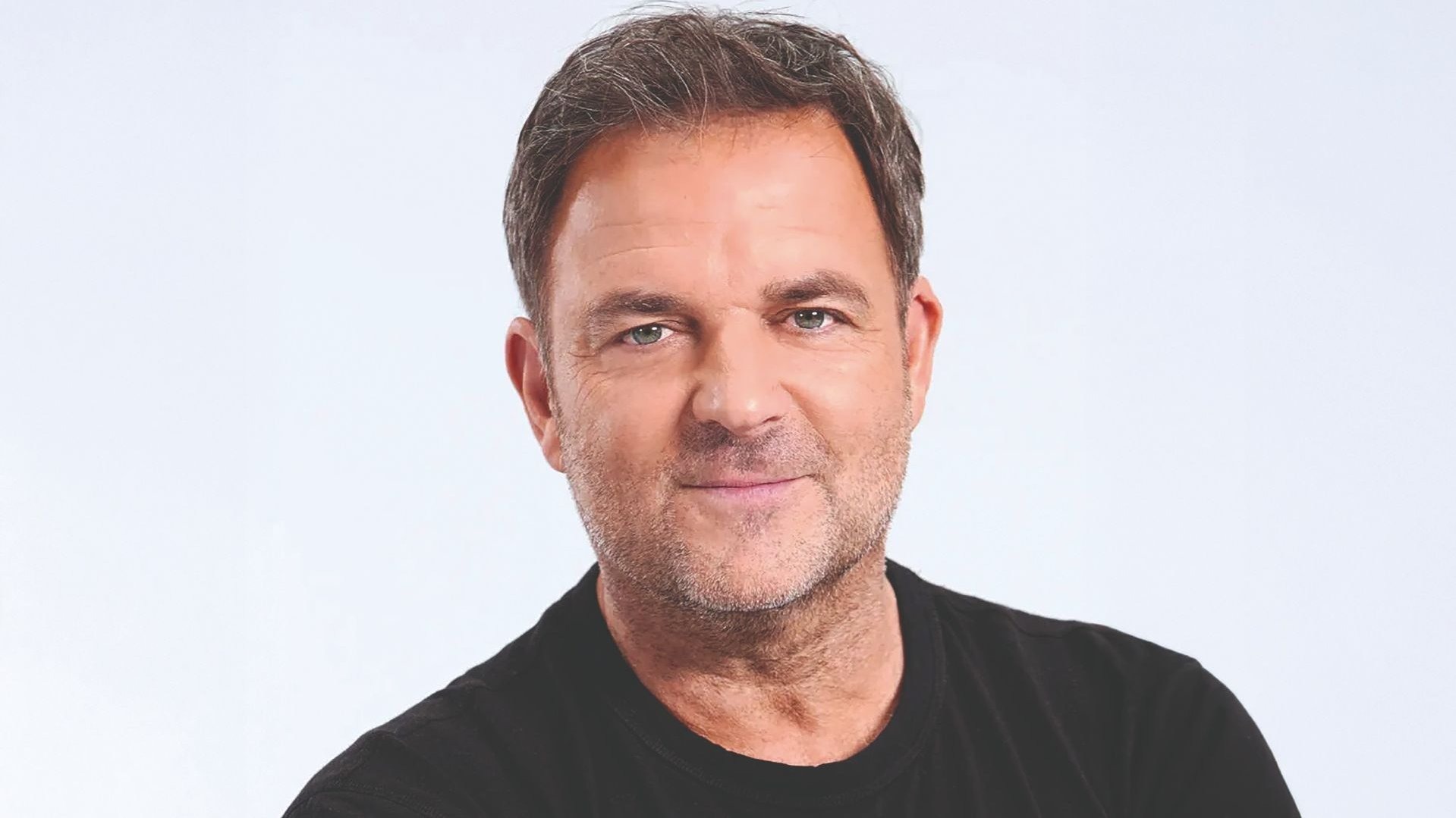 Martin Rütter mit kurzem Bart und braunem Haar, lächelt freundlich und trägt ein schwarzes T-Shirt
