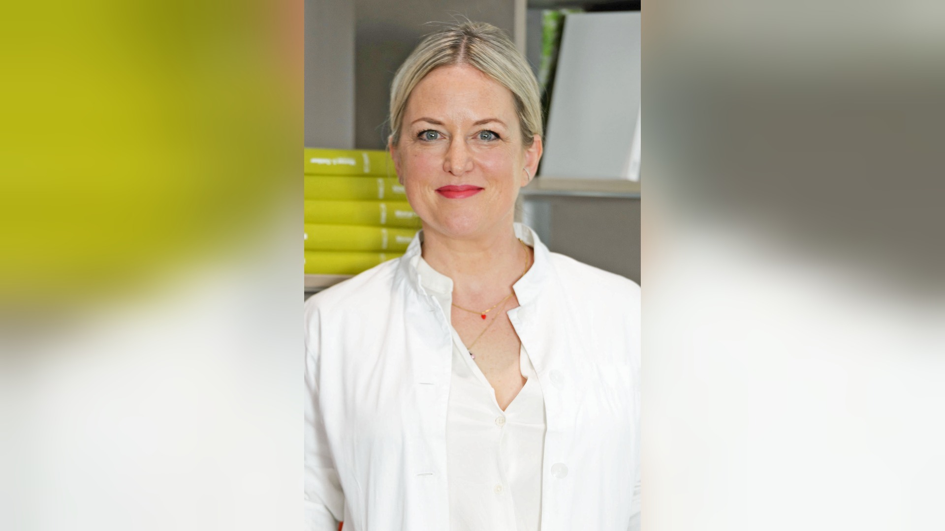 Apothekerin Ann-Kathrin Pause mit weißem Laborkittel lächelt in die Kamera vor unscharfem Regalhintergrund