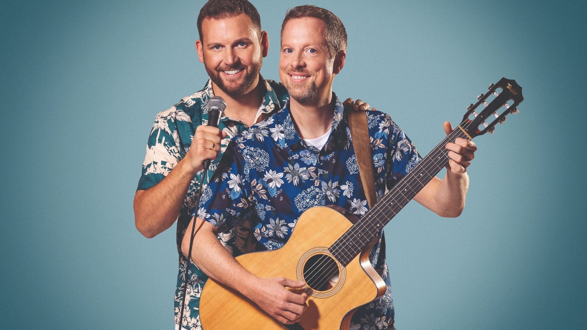 Zwei lächelnde Männer von Reis Against The Spülmachine in Hawaiihemden, einer mit Mikrofon, der andere mit Gitarre