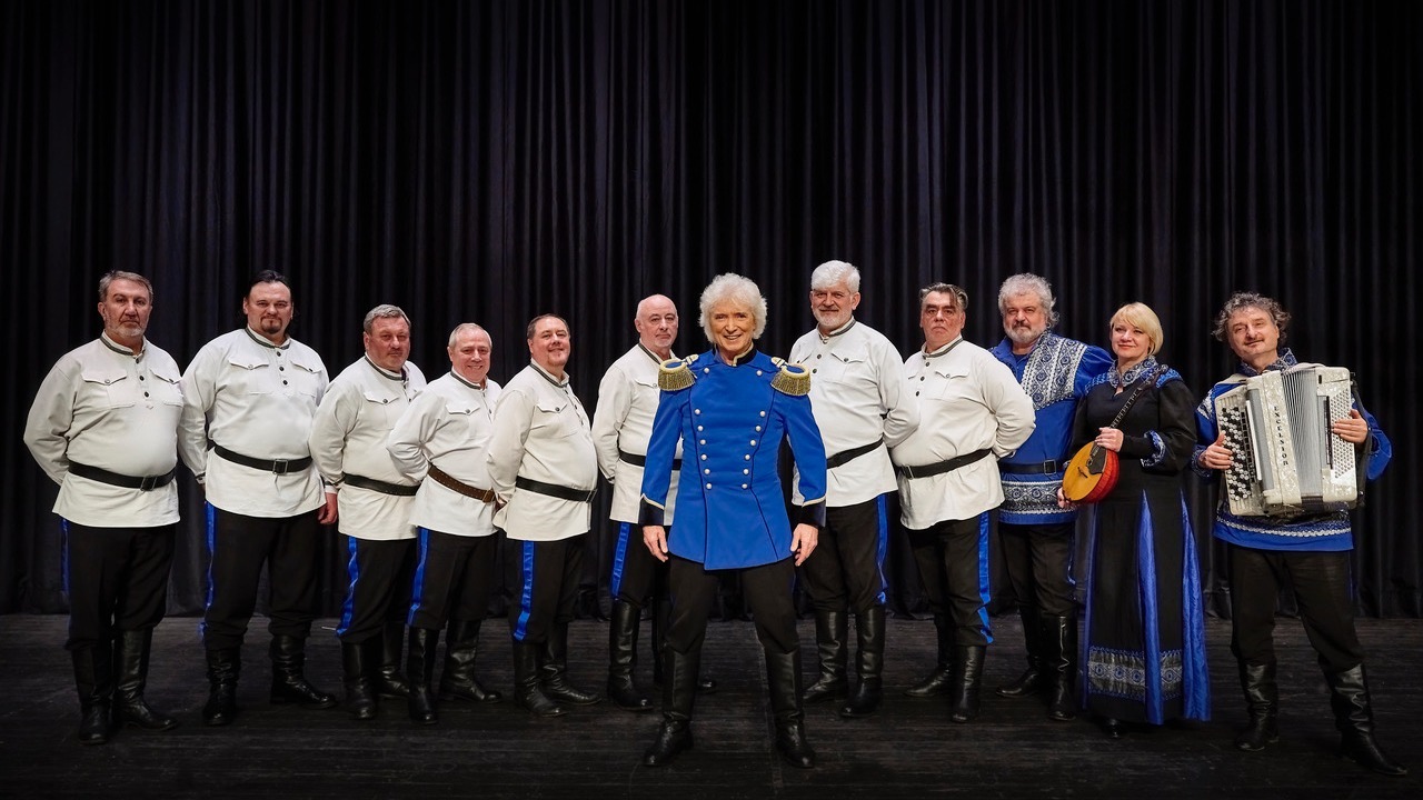 Peter Orloff in blauer Uniformjacke und zehn Mitglieder des Kosaken Chors mit Akkordeon und Balalaika auf der Bühne