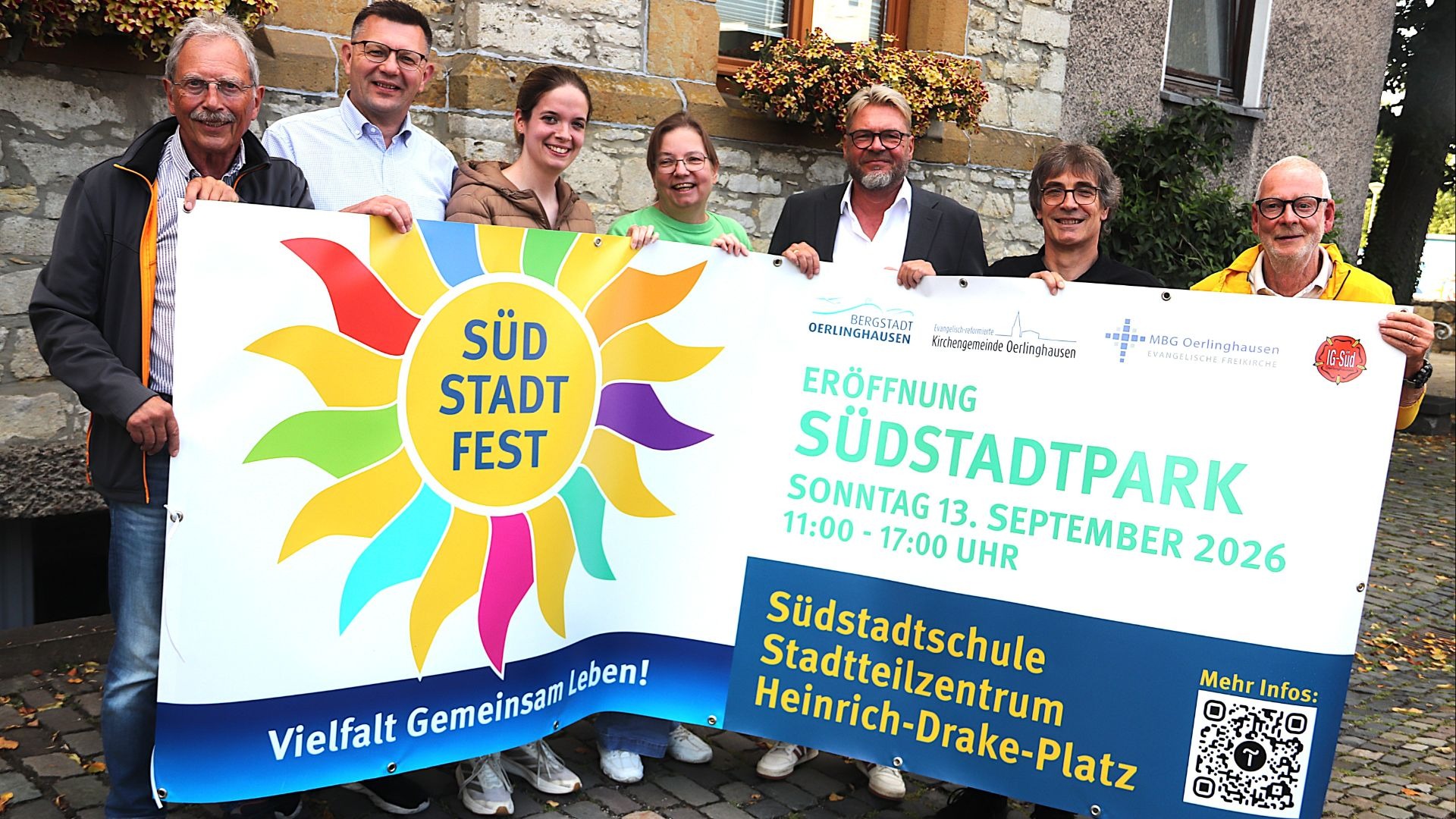 Sieben lächelnde Personen halten ein großes weißes Banner mit der Aufschrift „Südstadt Fest“ und „Eröffnung