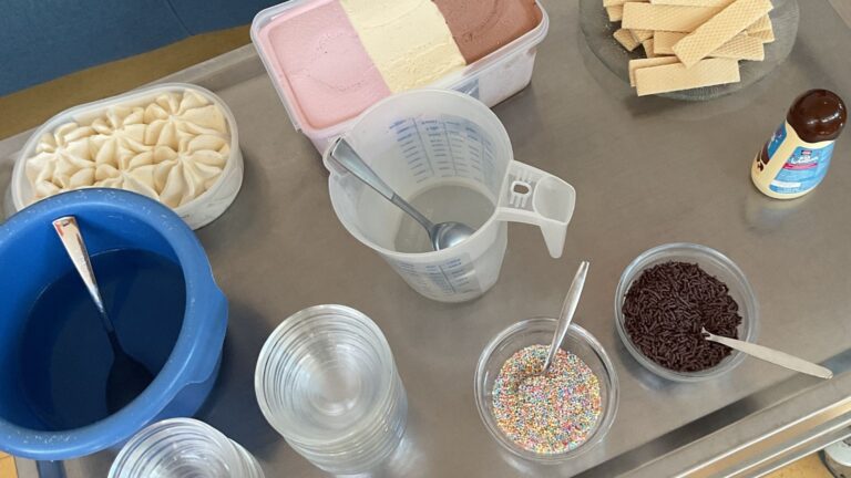 Servierwagen mit Behälter Neapolitaner Eis, Waffeln, Schoko- und bunten Streuseln, Schokosoße, Löffeln und Gläsern