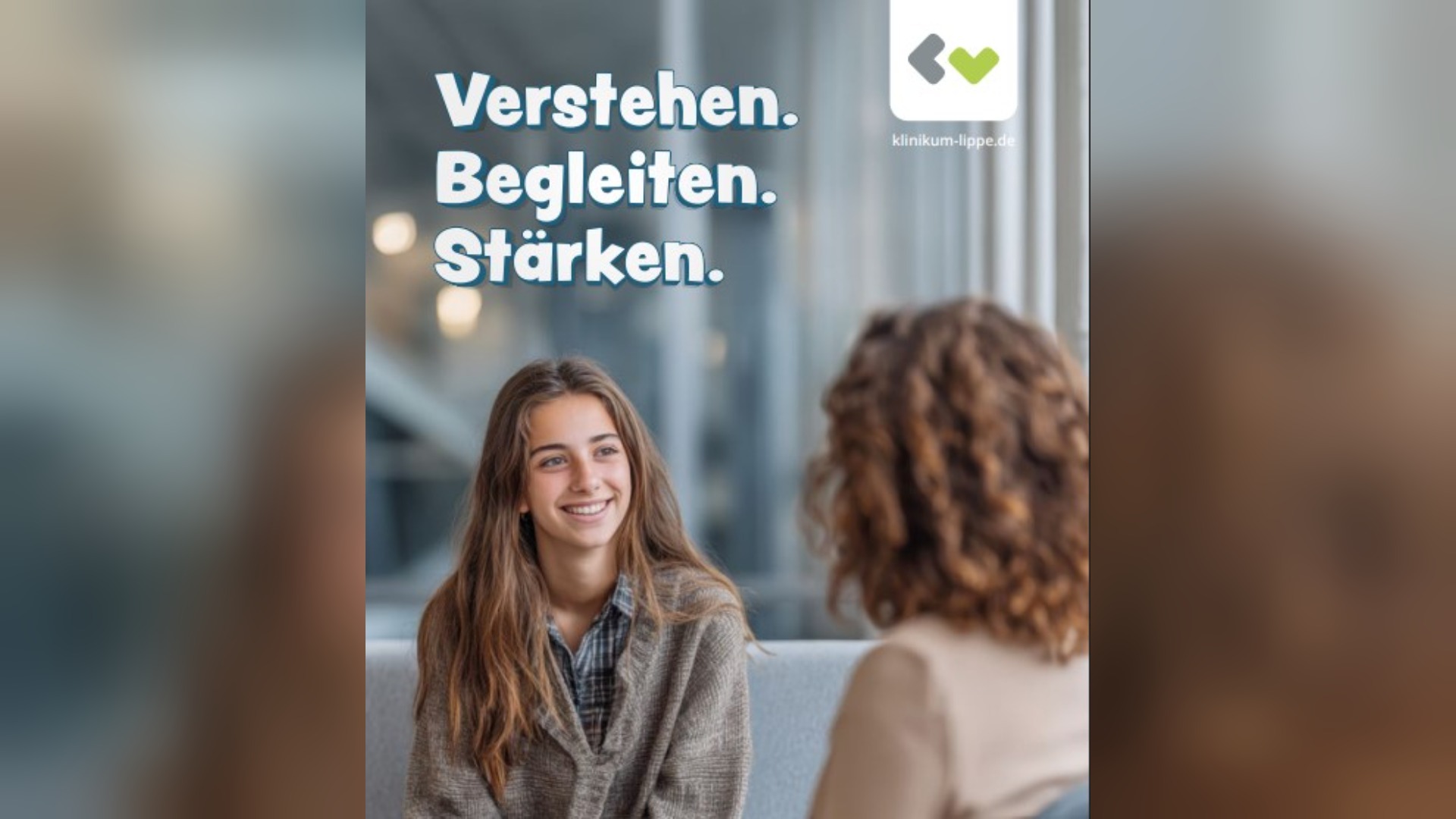 Lächelnde junge Frau im Gespräch mit einer Person, die mit dem Rücken zum Betrachter sitzt