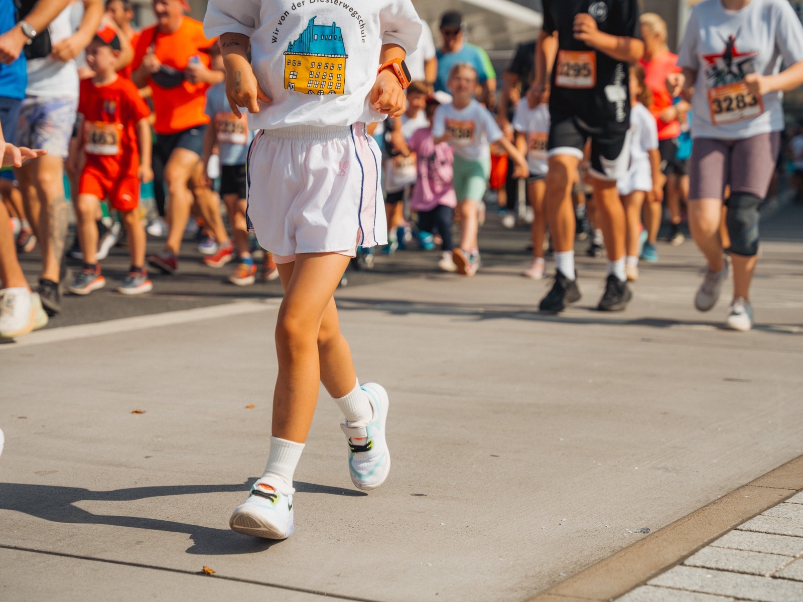 Eine Gruppe von Kindern und Erwachsenen rennt bei einem Laufwettbewerb auf einer Straße