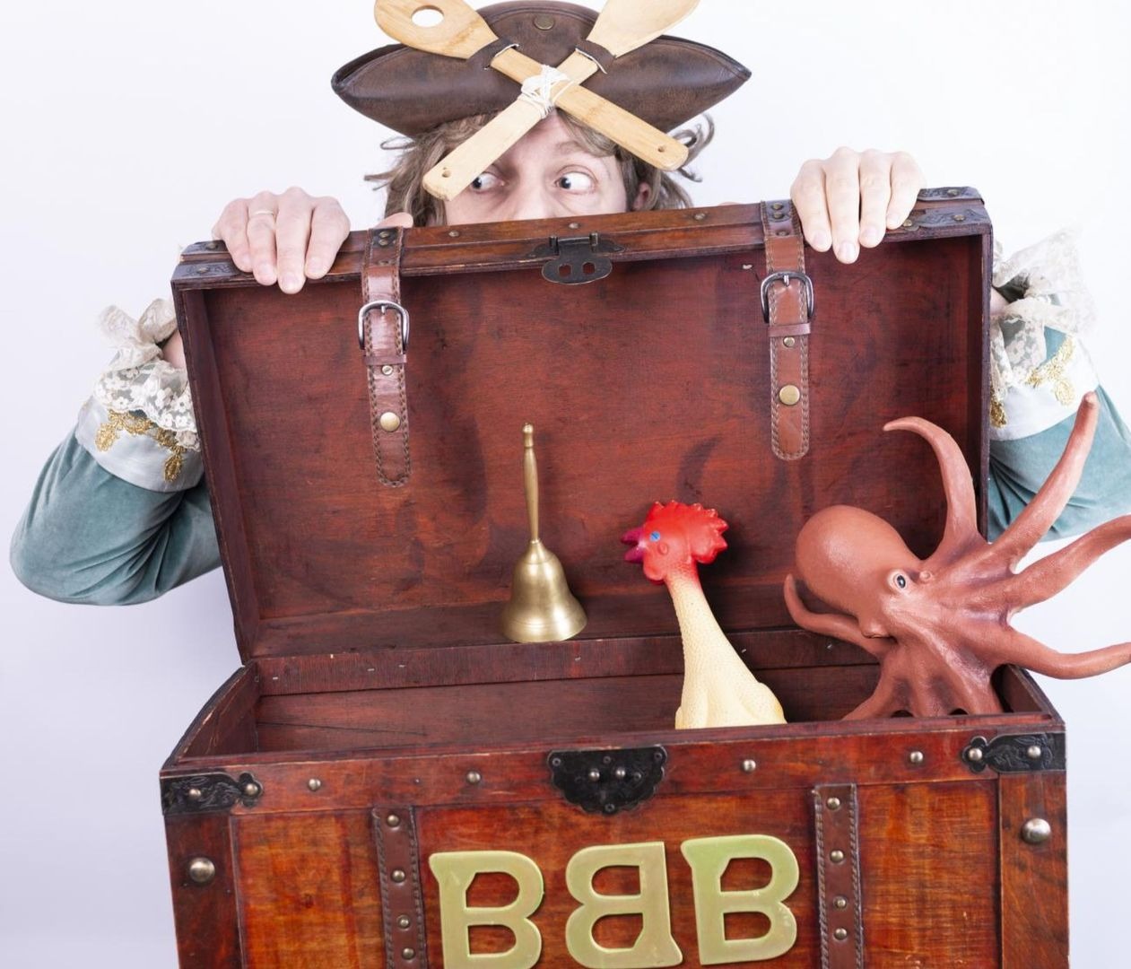 Pirat Backen-Bart-Bernd mit Löffelhut lugt hinter einer Schatztruhe mit Glocke, Huhn und Oktopus hervor