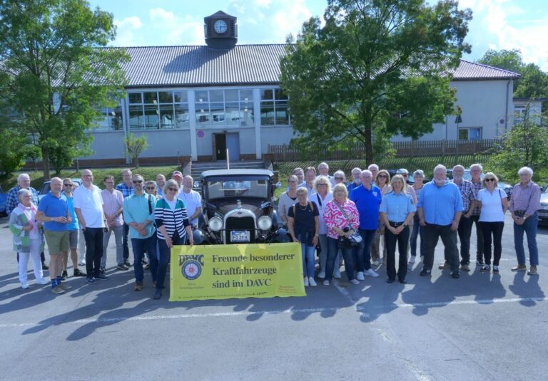 DAVC-Gruppe und Polizistin mit Oldtimer und gelbem Banner vor dem Gebäude der Bundespolizei mit Uhr