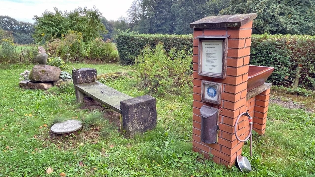 Kneipp-Wassertretstelle aus Ziegelstein mit Becken, Infotafel und Holzbank an einem Naturpfad beim Kloster St. Raphael