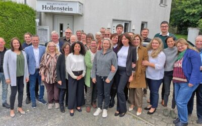 Etwa 25 Frauen und Männer stehen lächelnd vor dem Bergrestaurant Hollenstein